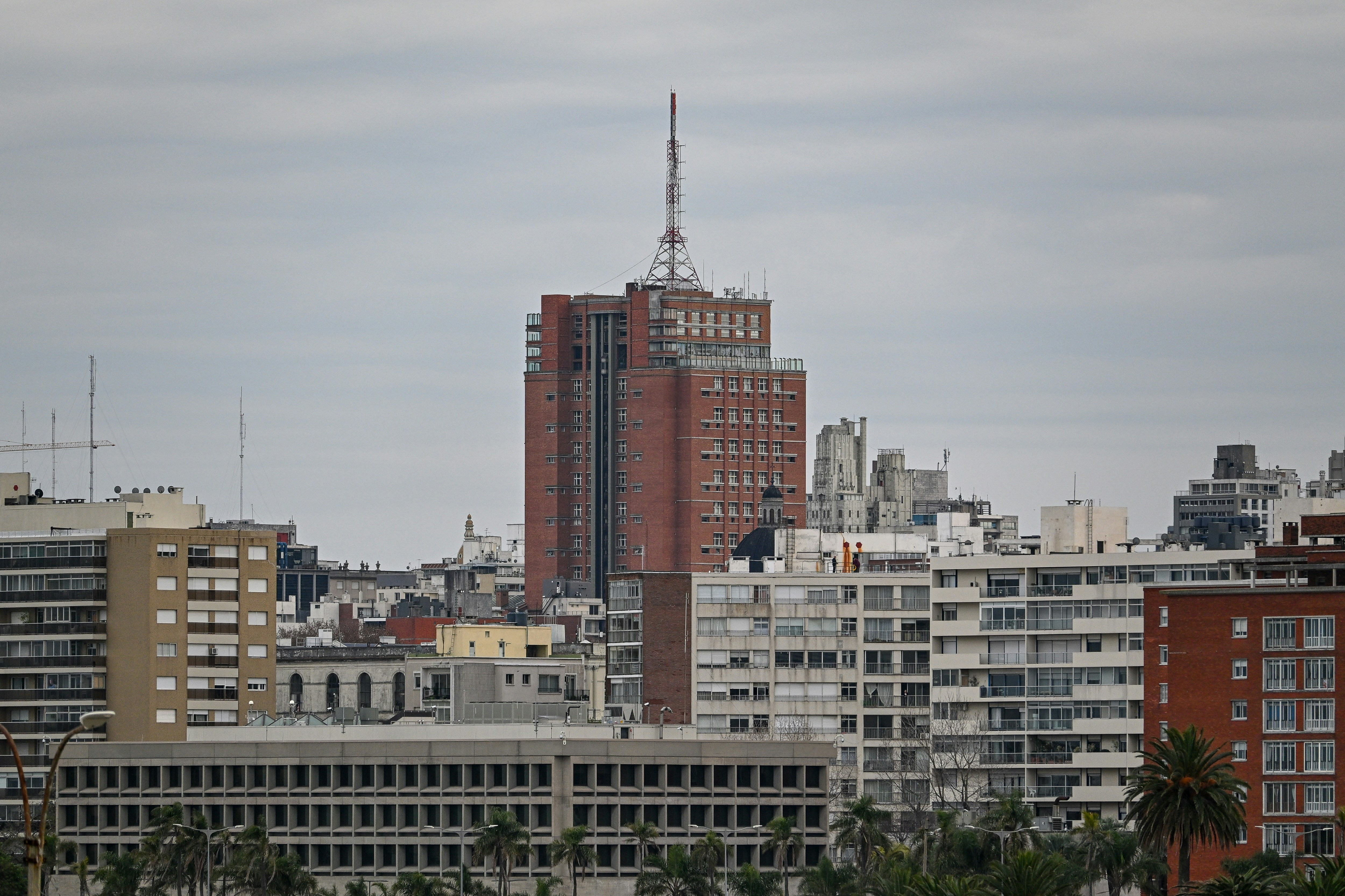 Cloudy cityscape with a prominent tall reddish-brown building.