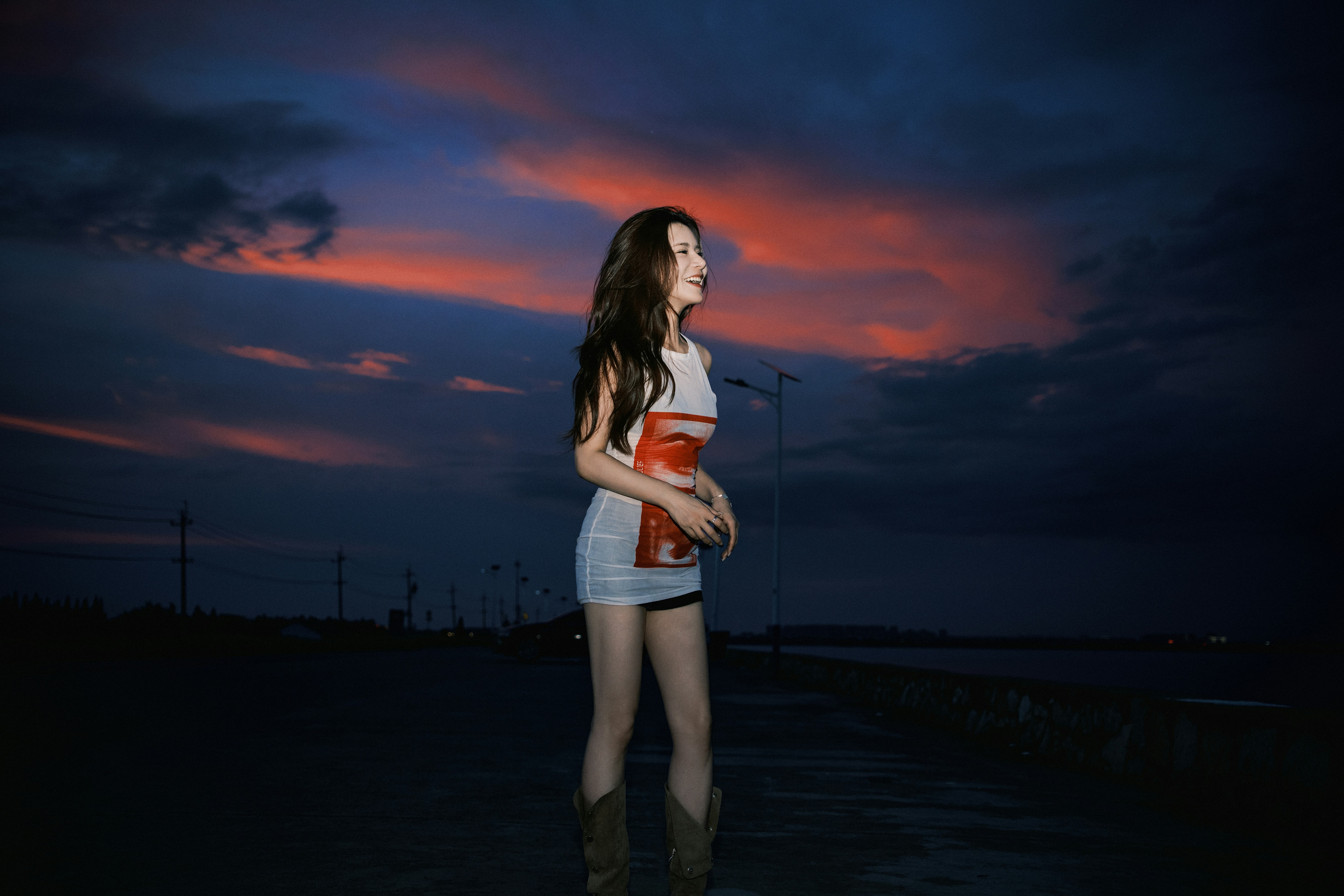 Woman in dress standing outdoors during a colorful sunset