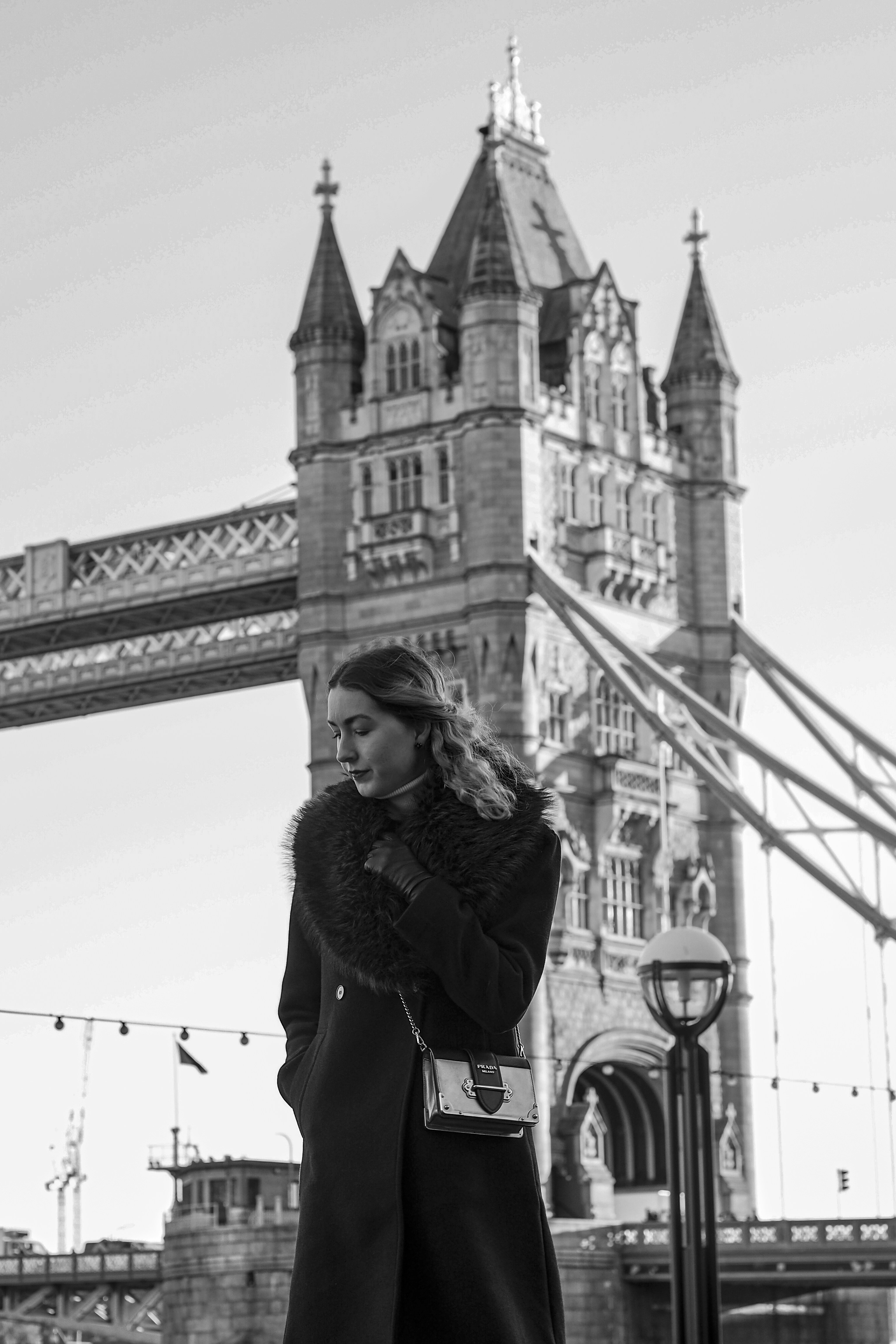 Mulher elegante posando perto da ponte da torre em monocromático