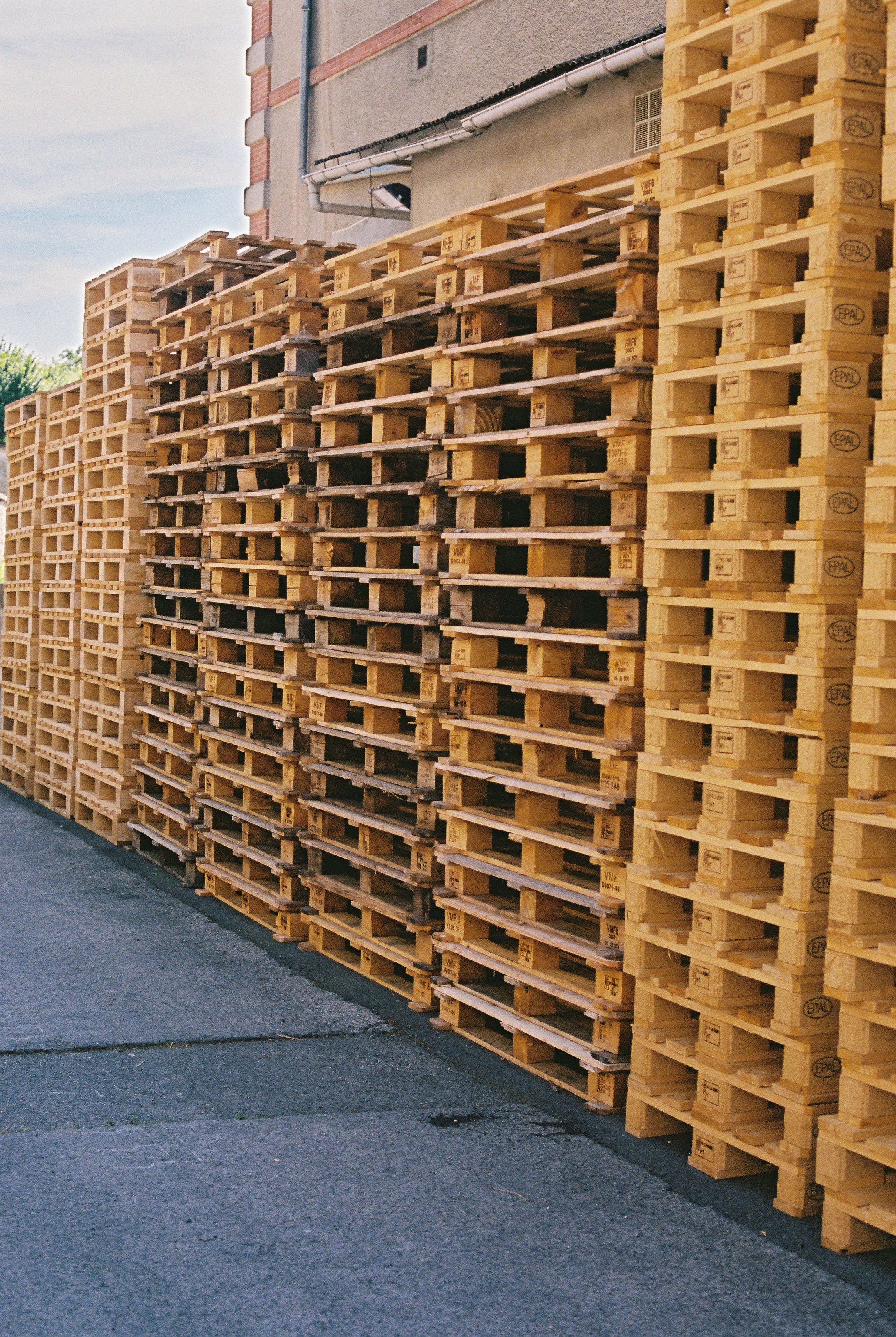 Wooden pallets stacked high against a building