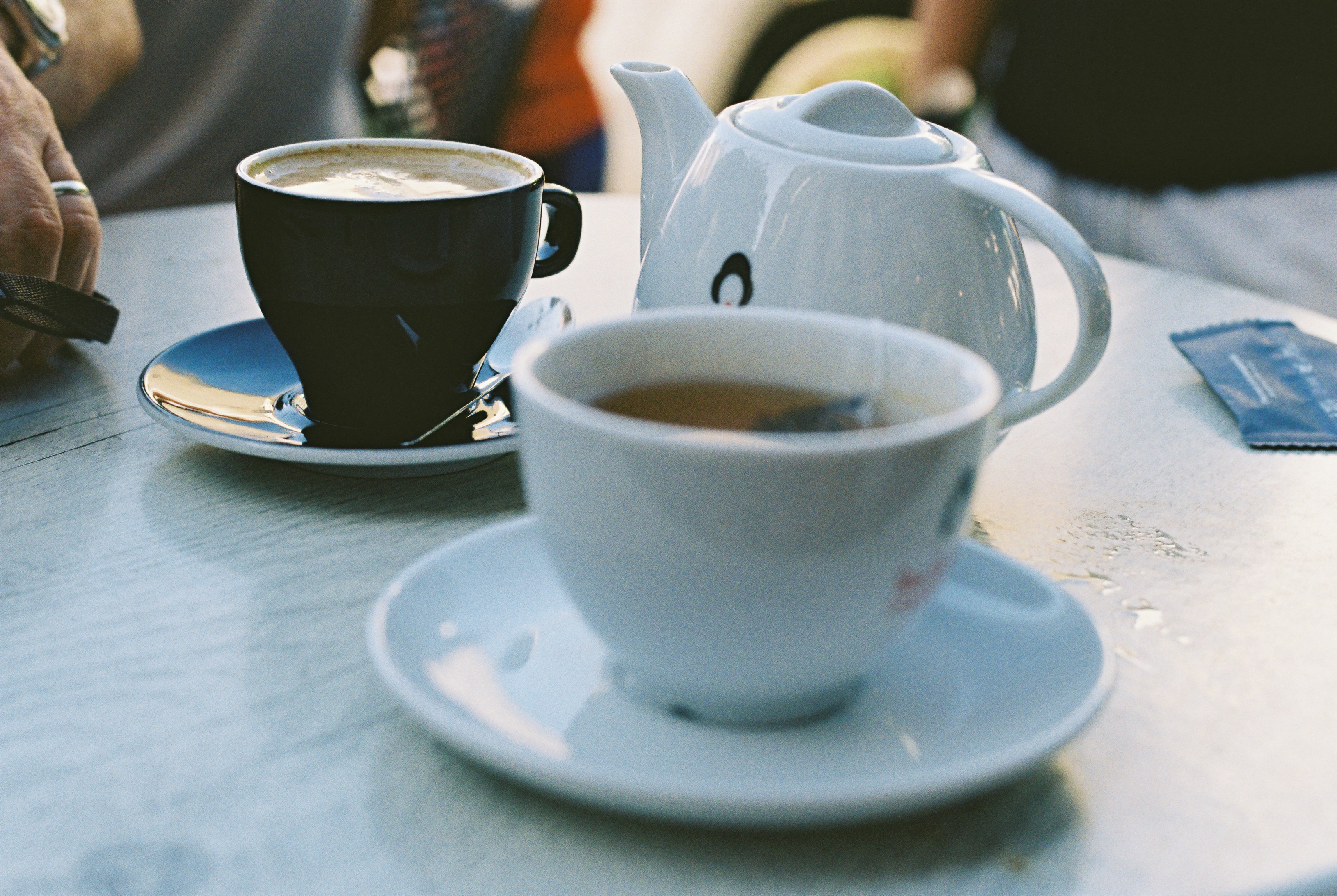 Coffee and tea cups with a teapot on a table