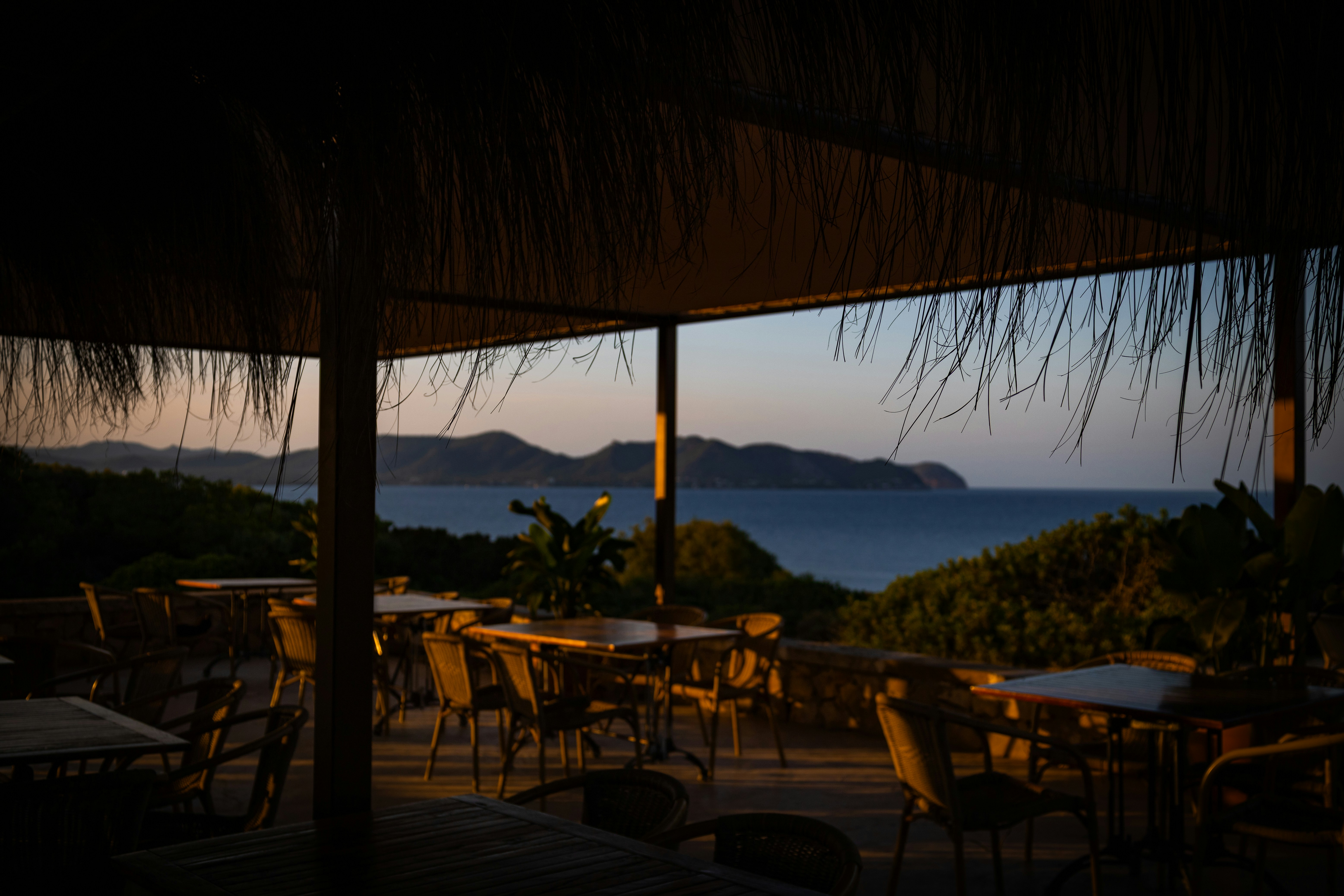 An outdoor restaurant overlooking the ocean at sunset
