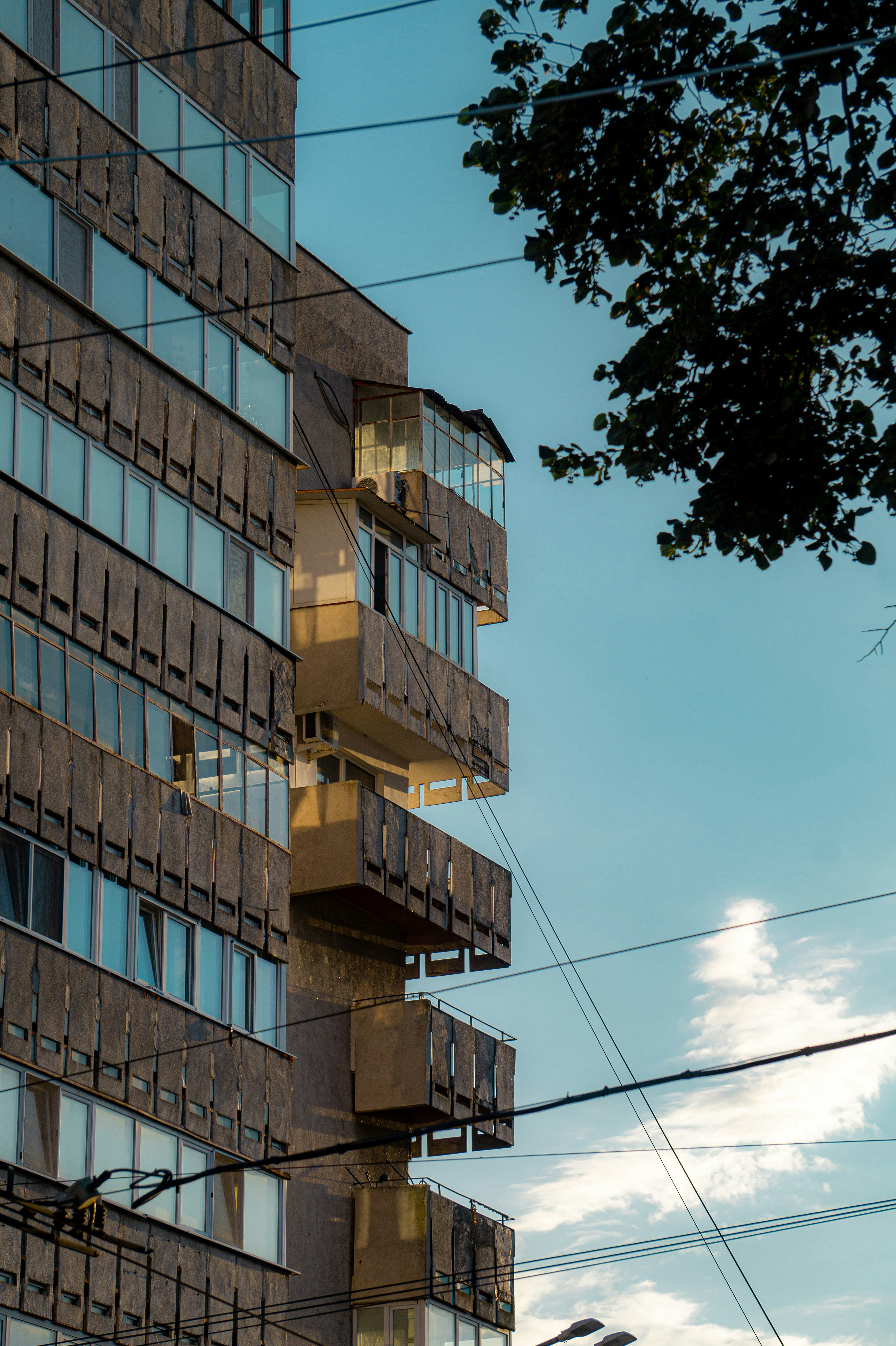 Edificio alto con balconi e linee elettriche contro il cielo azzurro.