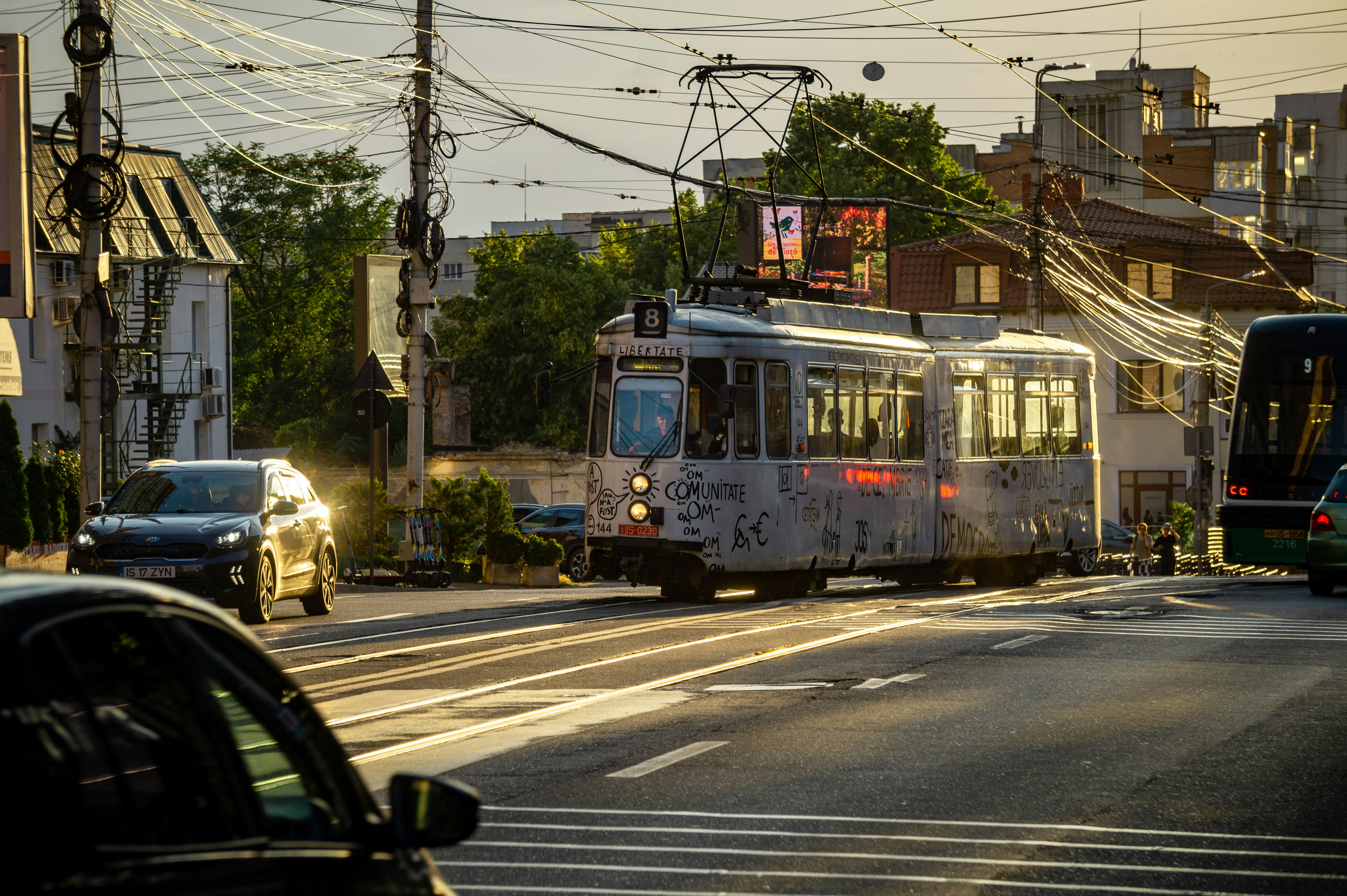 Un tram e auto su una strada cittadina al tramonto.