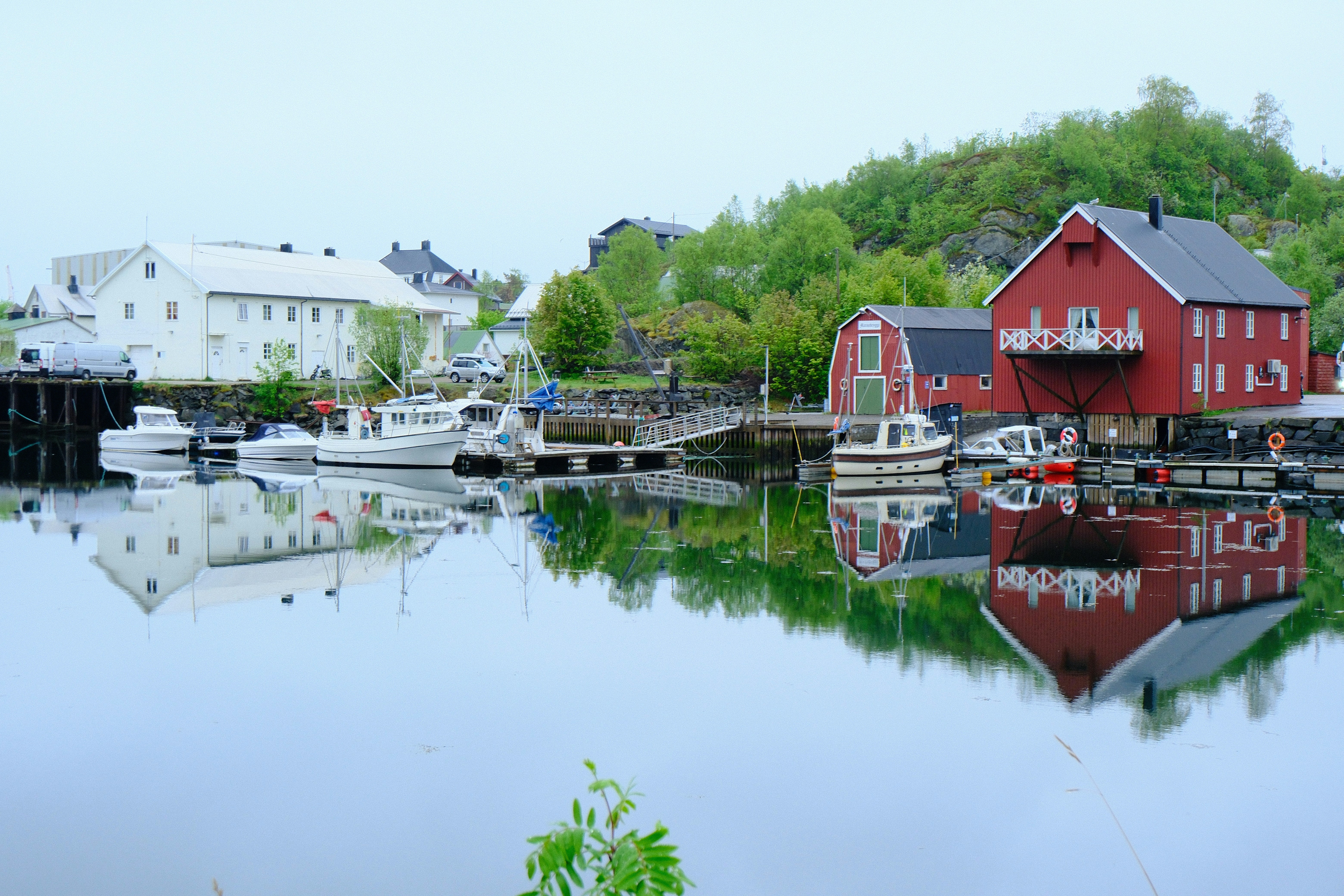 Red and white buildings with boats reflected in calm water