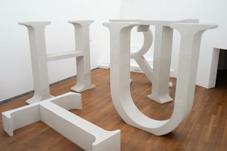 Large grey letters standing on a polished wooden floor.