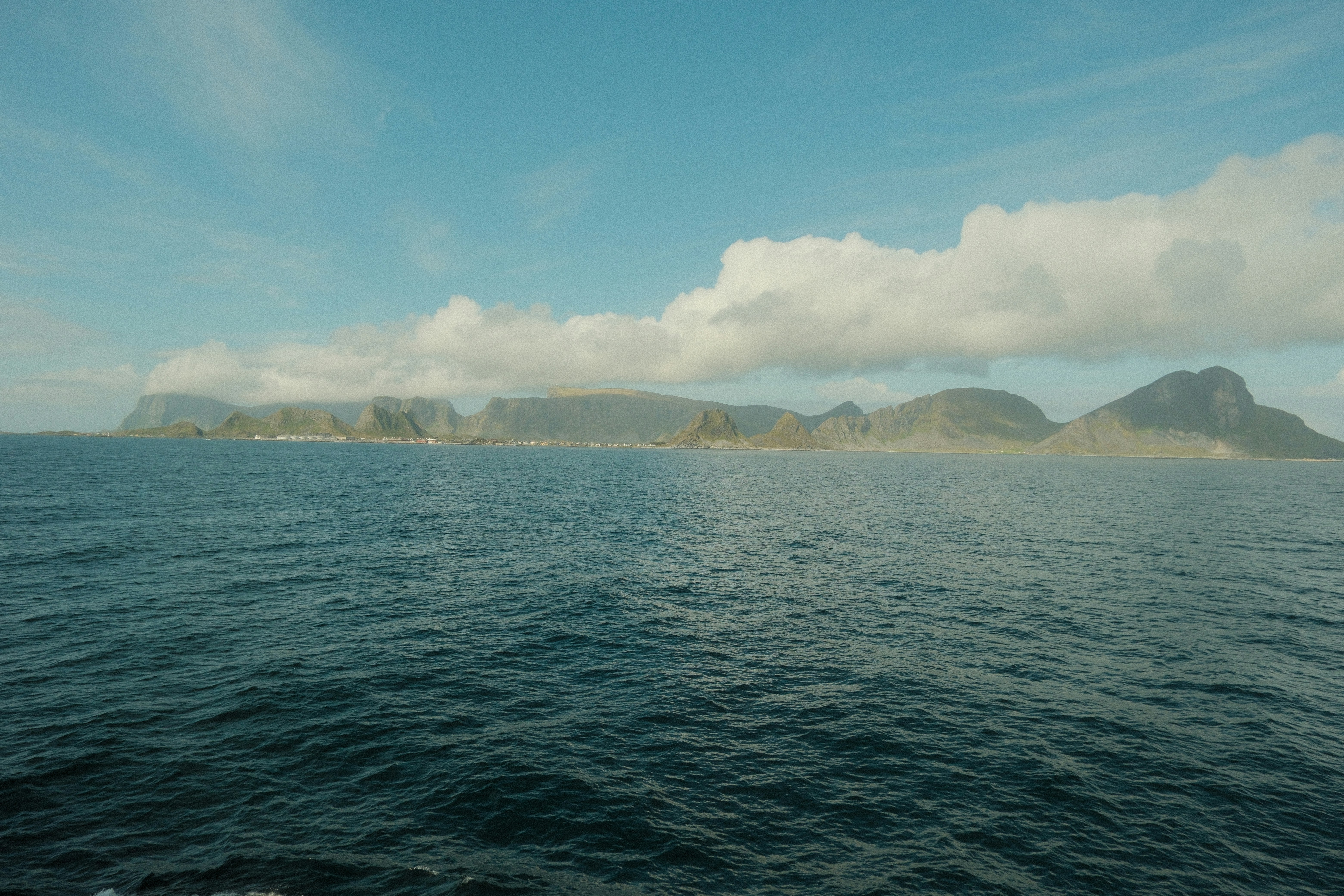 Vast blue ocean stretching towards a distant mountainous coastline
