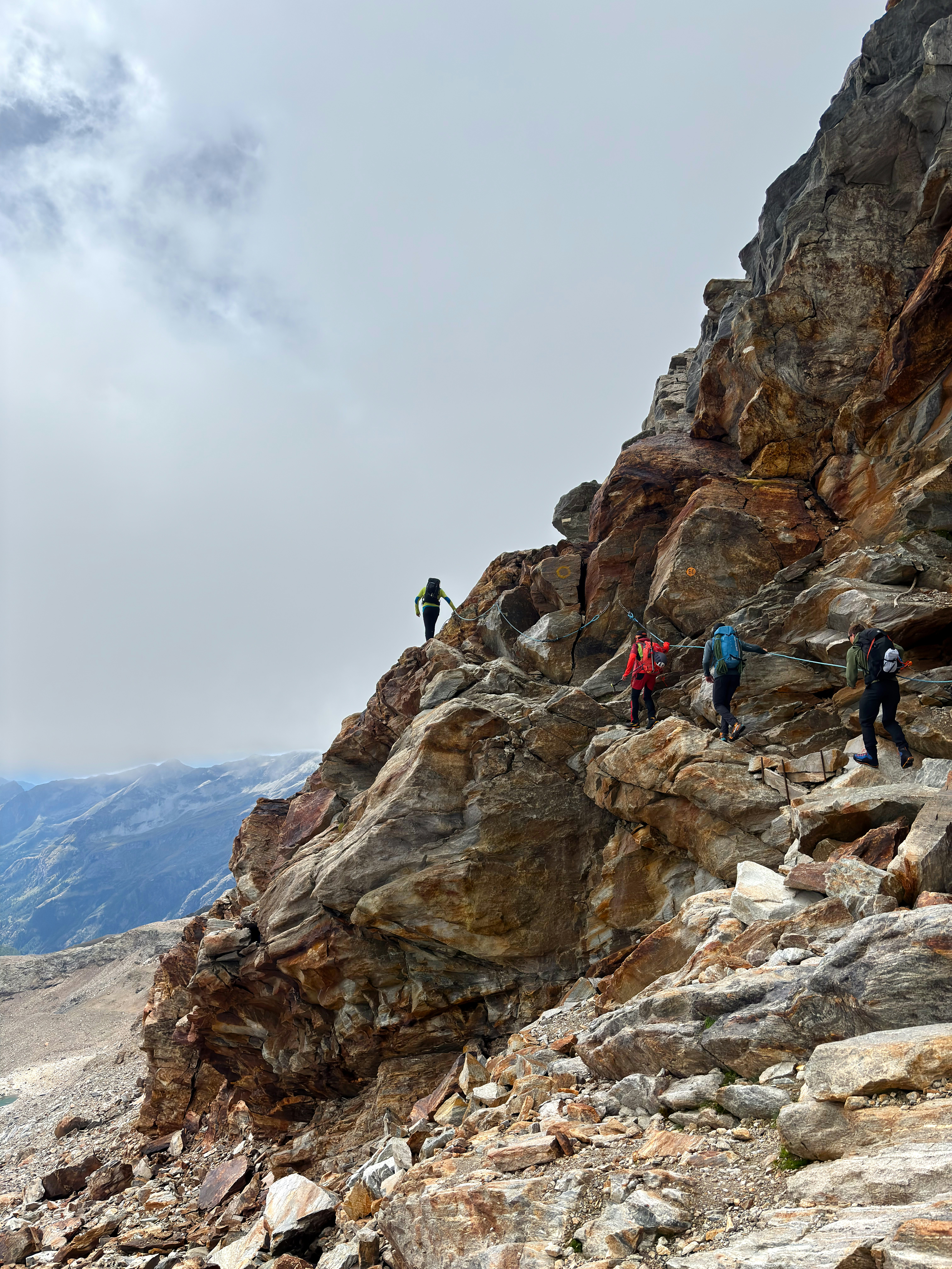 Hikers traverse a steep, rocky mountain path