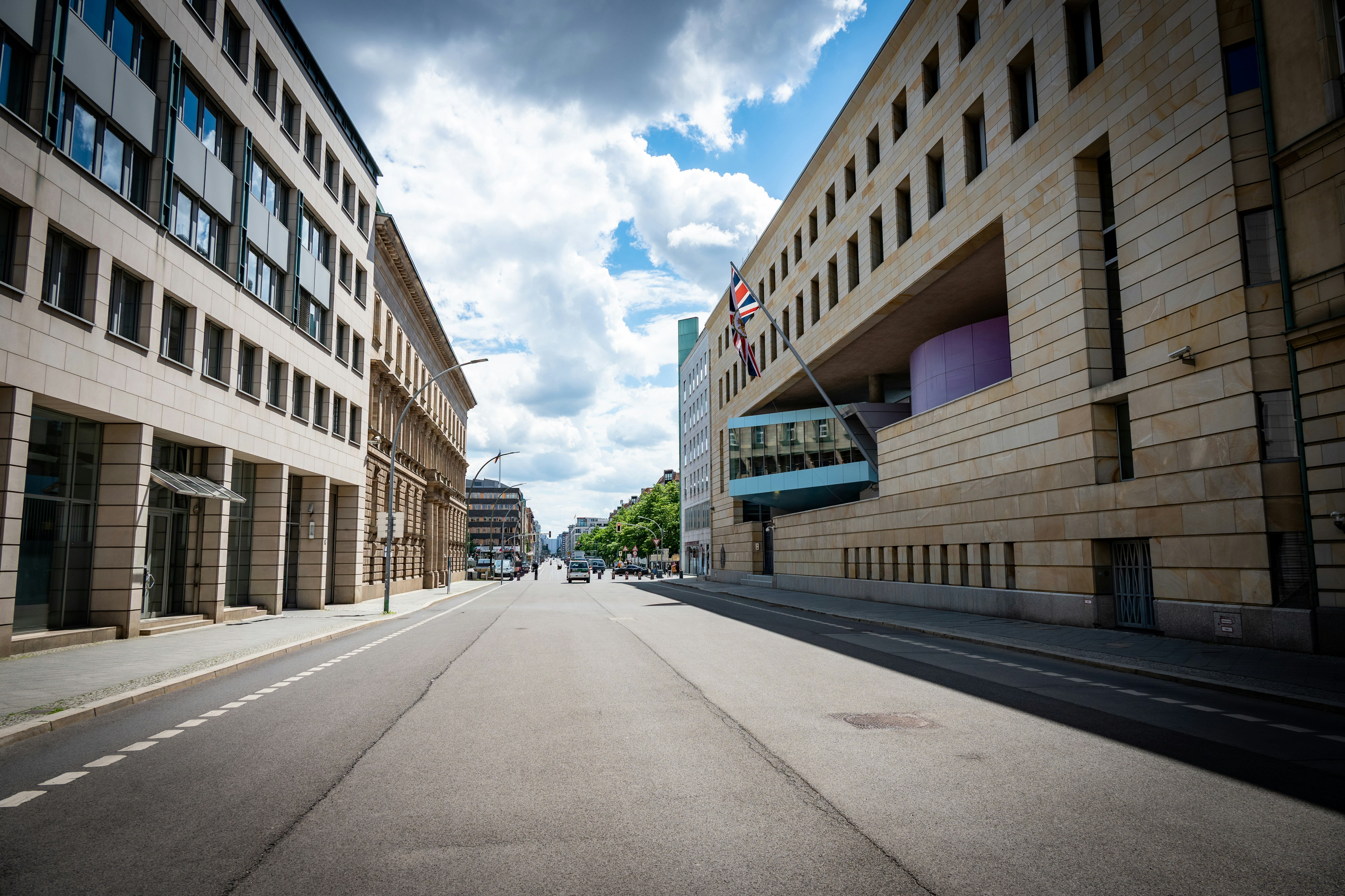 Empty city street with modern buildings under a cloudy sky.