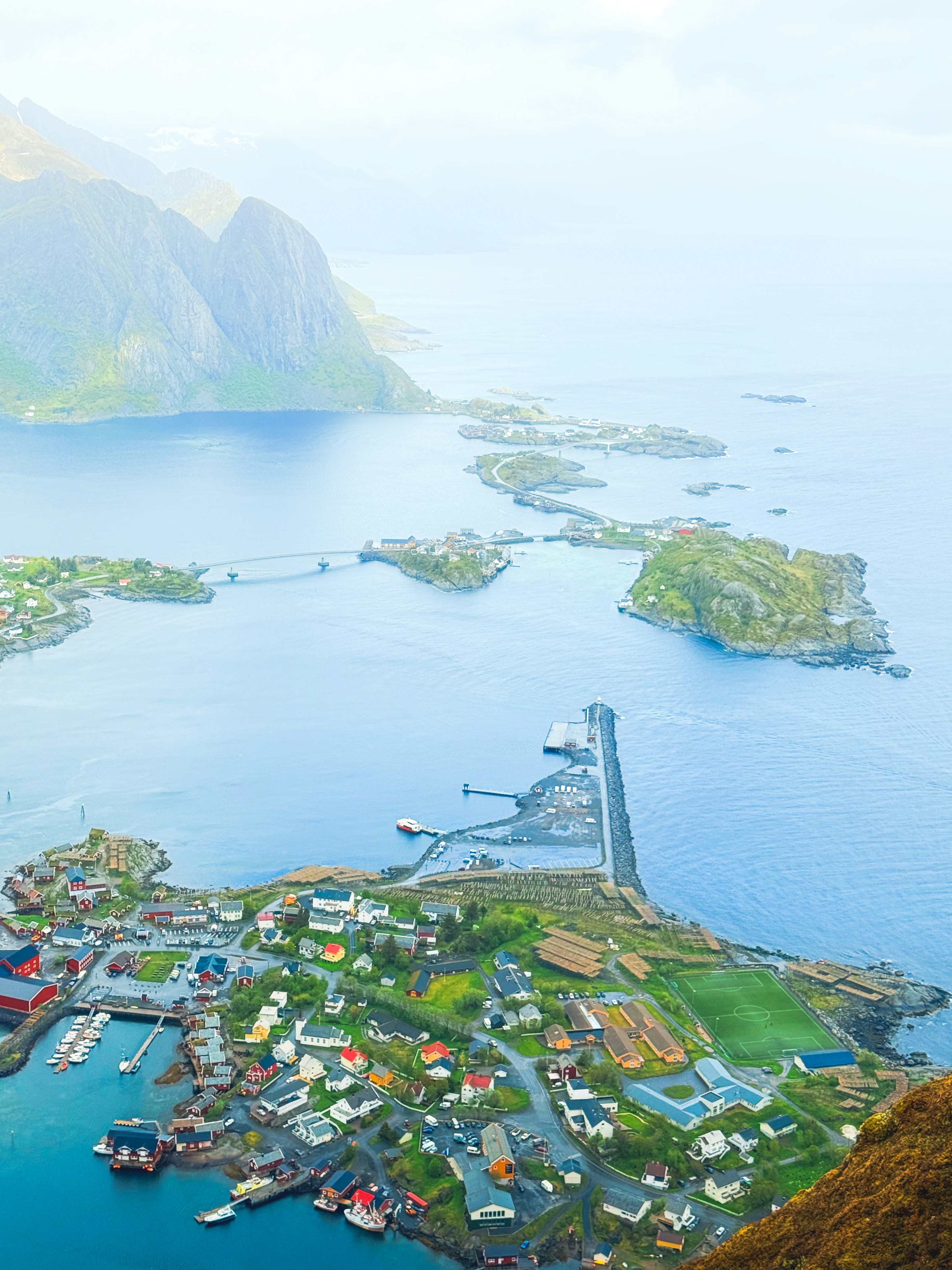 Aerial view of a coastal village with islands and mountains.