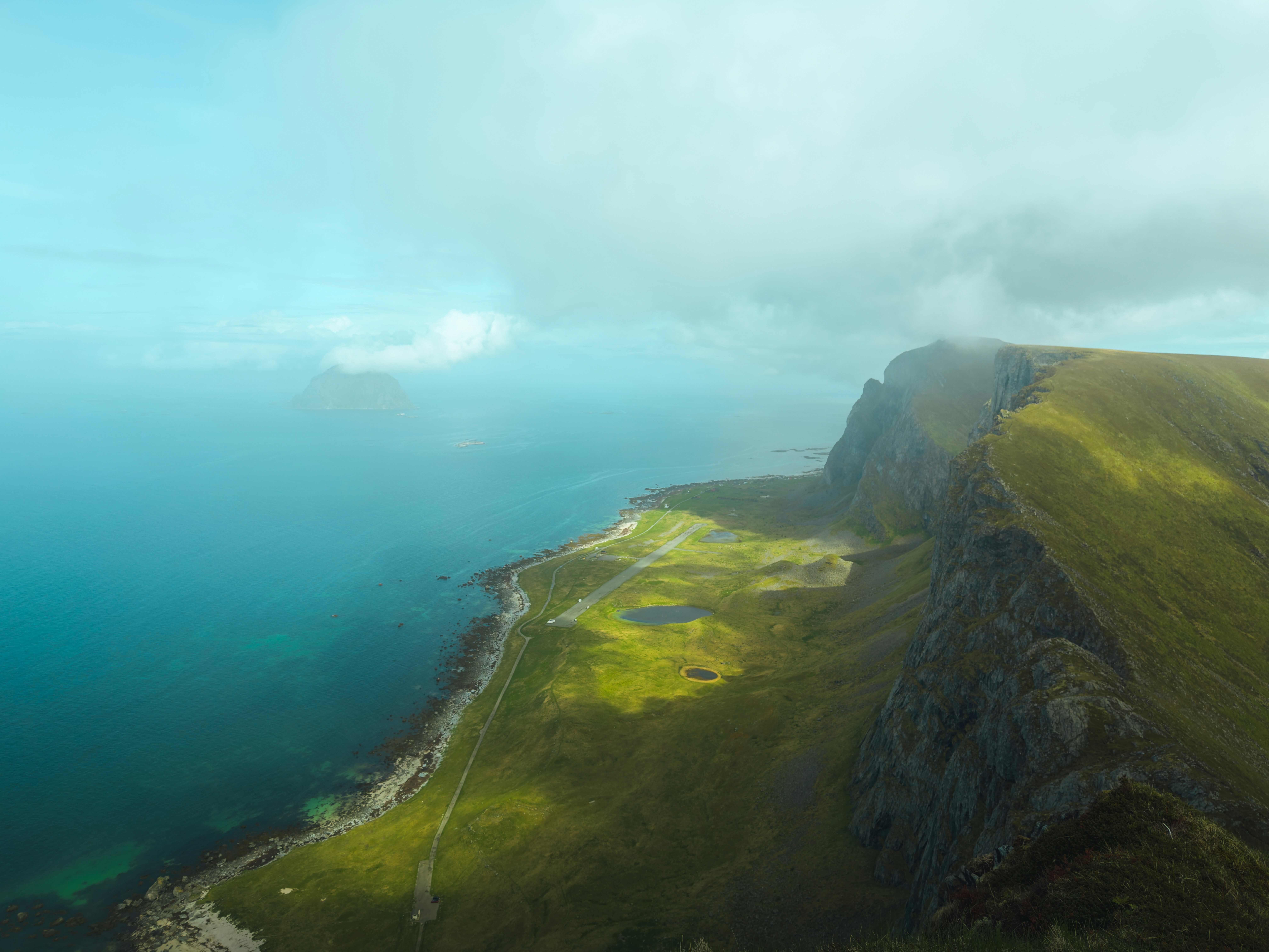 Dramatic green mountain landscape beside a vibrant blue ocean