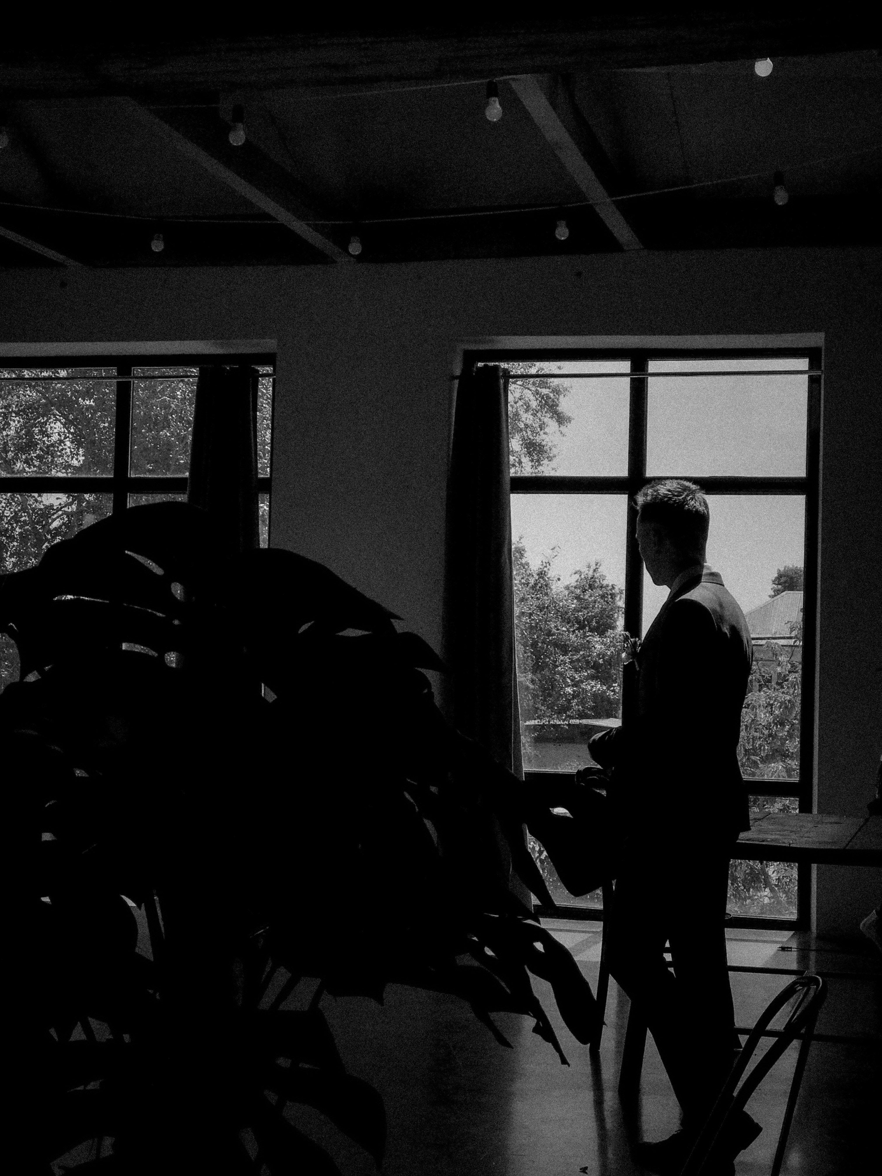Der Mann in Silhouette schaut schwarz-weiß aus dem Fenster