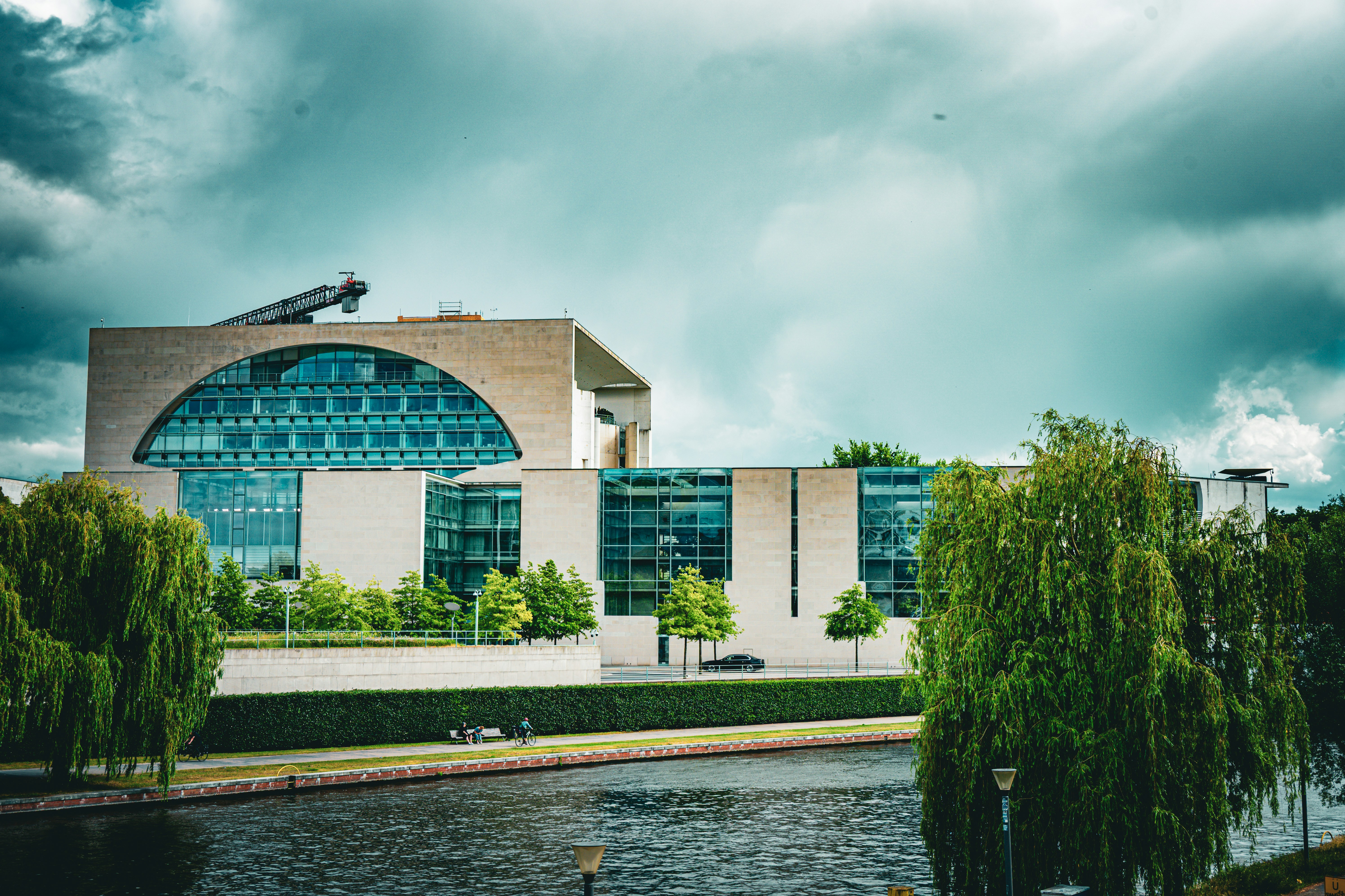 Modern building with curved glass facade by a river.