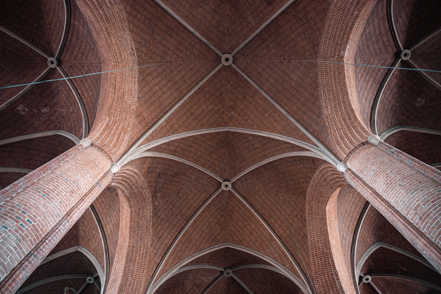 A brick vaulted ceiling with intersecting ribs photographed straight up from the floor