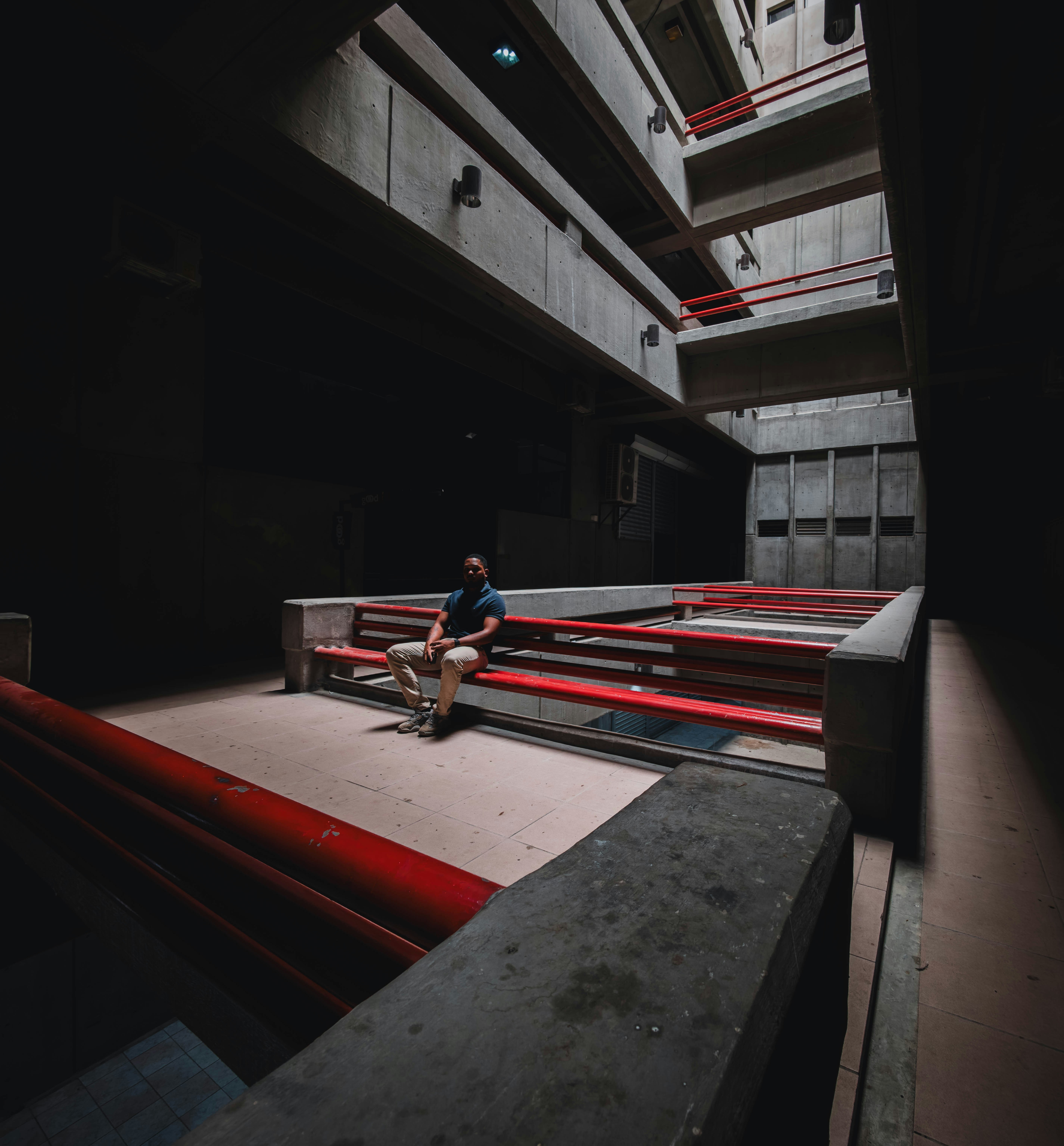 Man sits on red benches in a dark concrete building