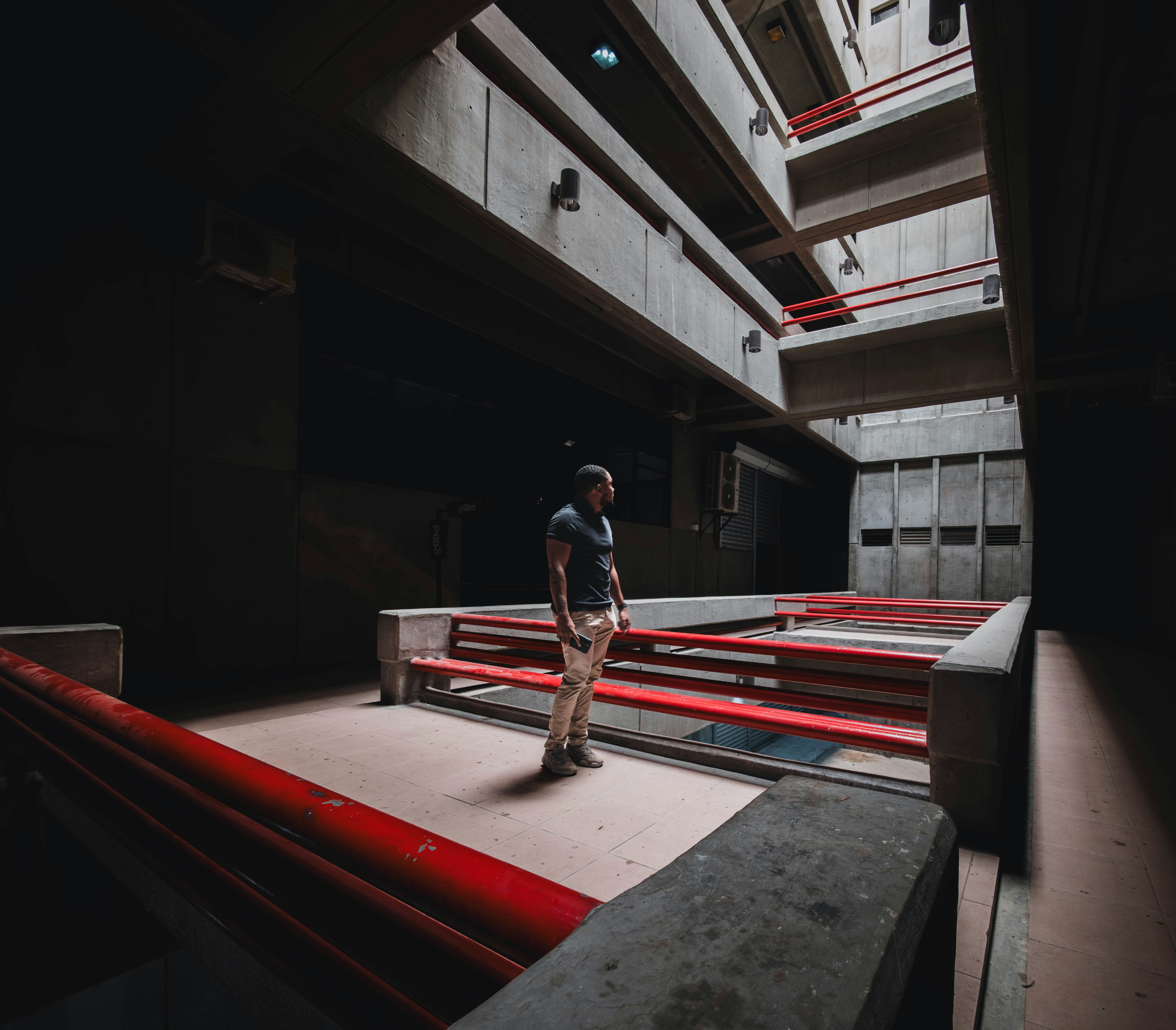 A man stands in a dark, brutalist concrete building