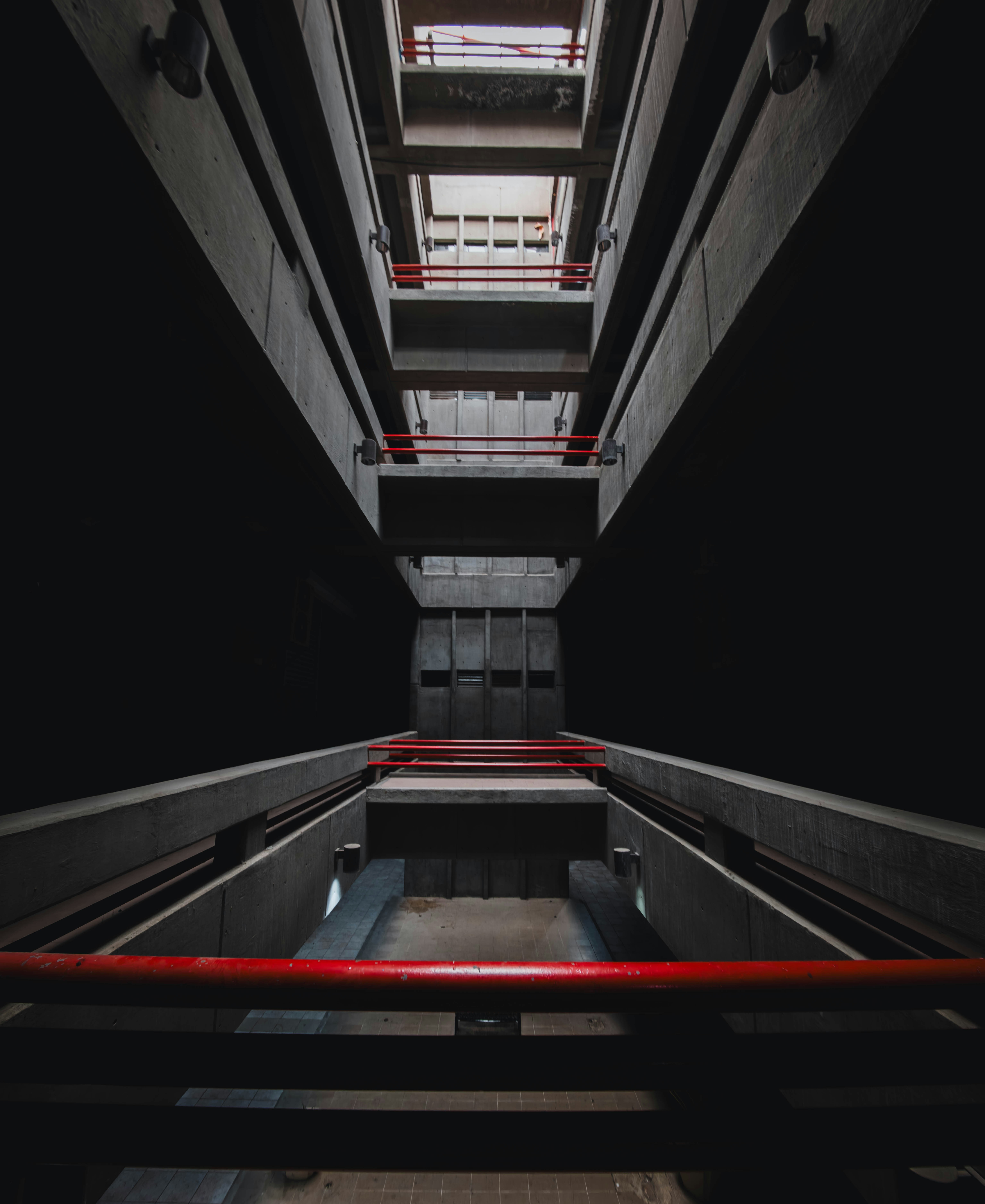 Looking up a concrete stairwell with red railings