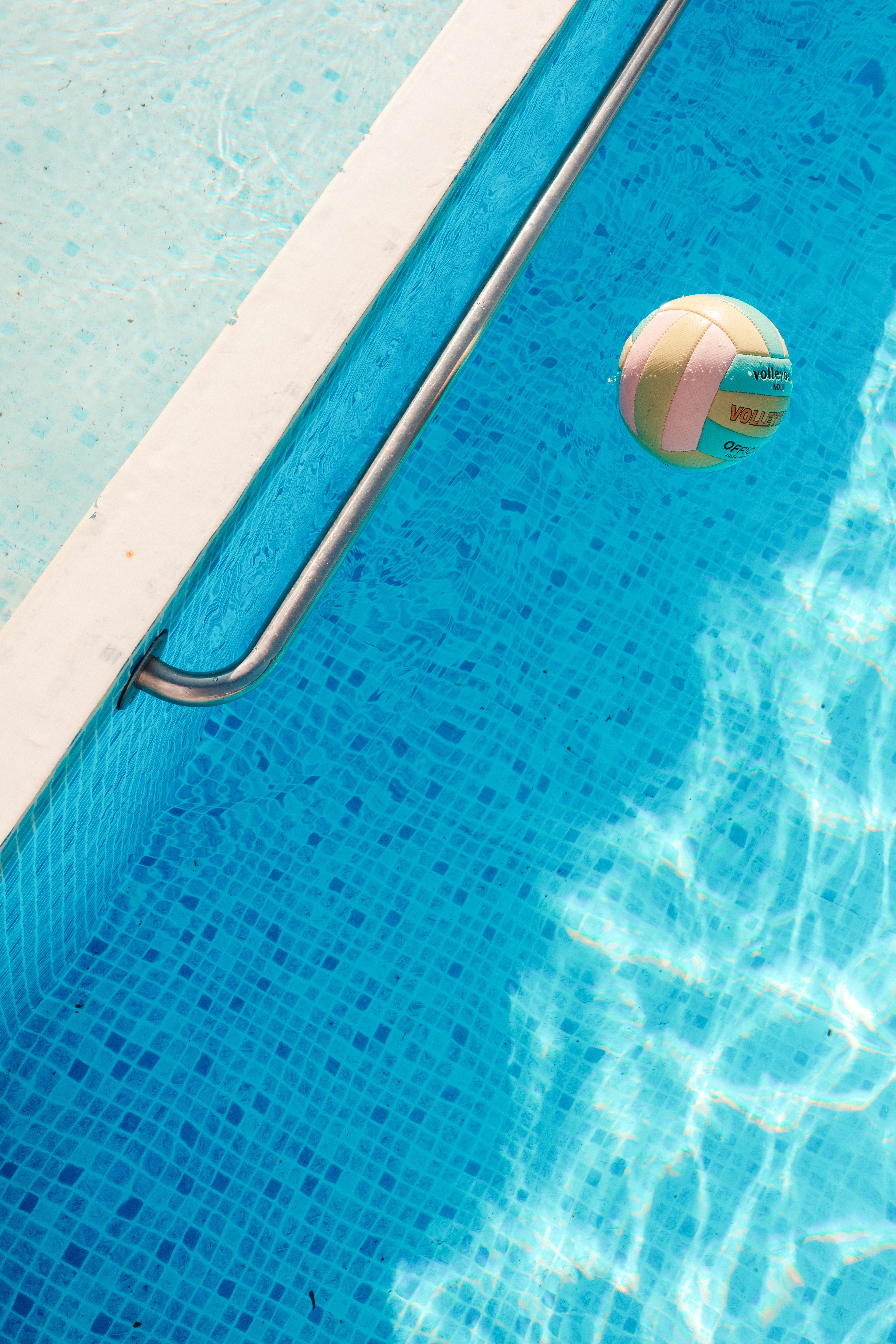 A colorful ball floats in a blue swimming pool.