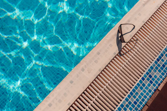 Swimming goggles resting on the edge of a blue pool.