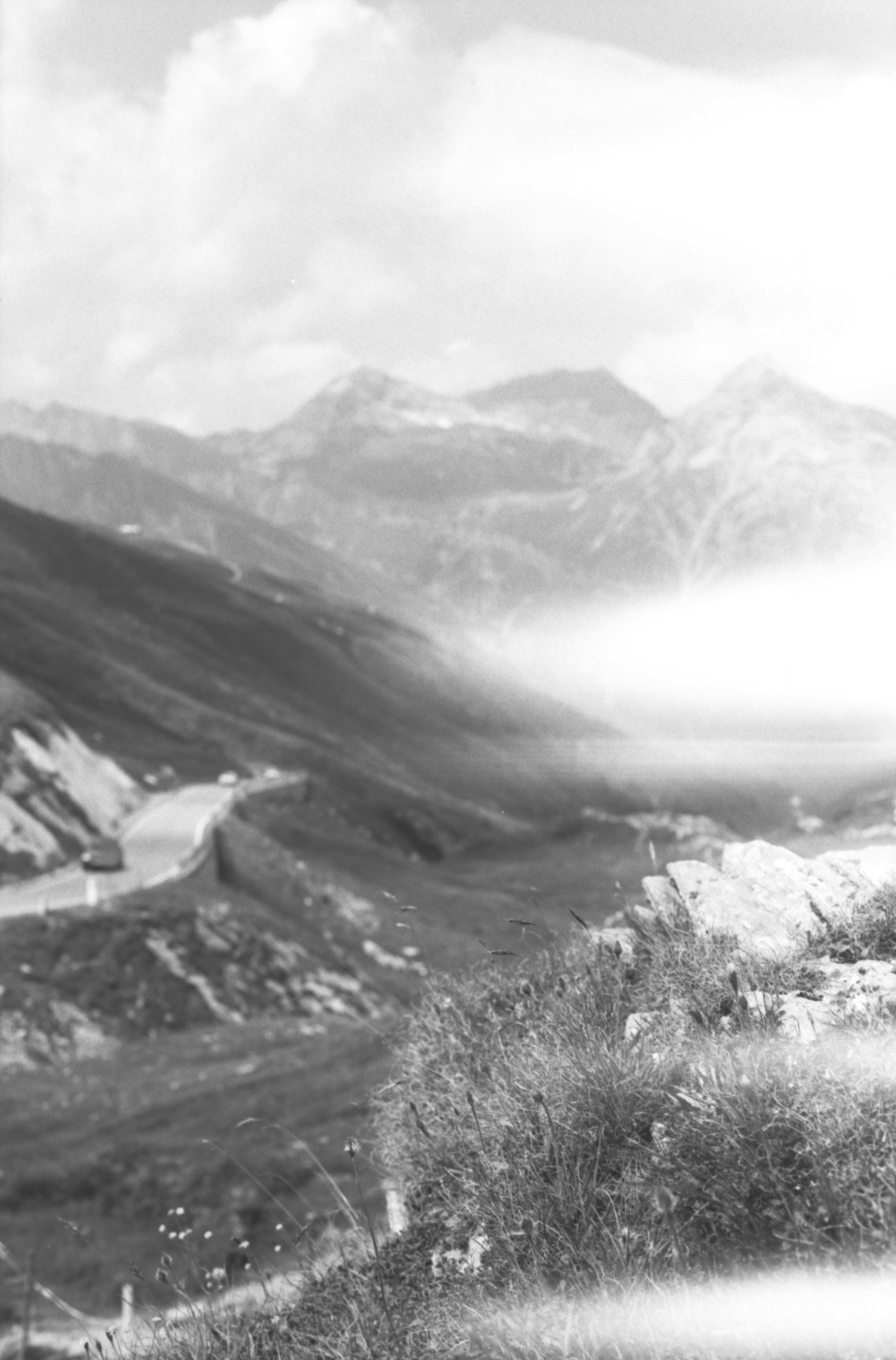 La strada di montagna tortuosa scompare tra vette nebbiose e aspre.
