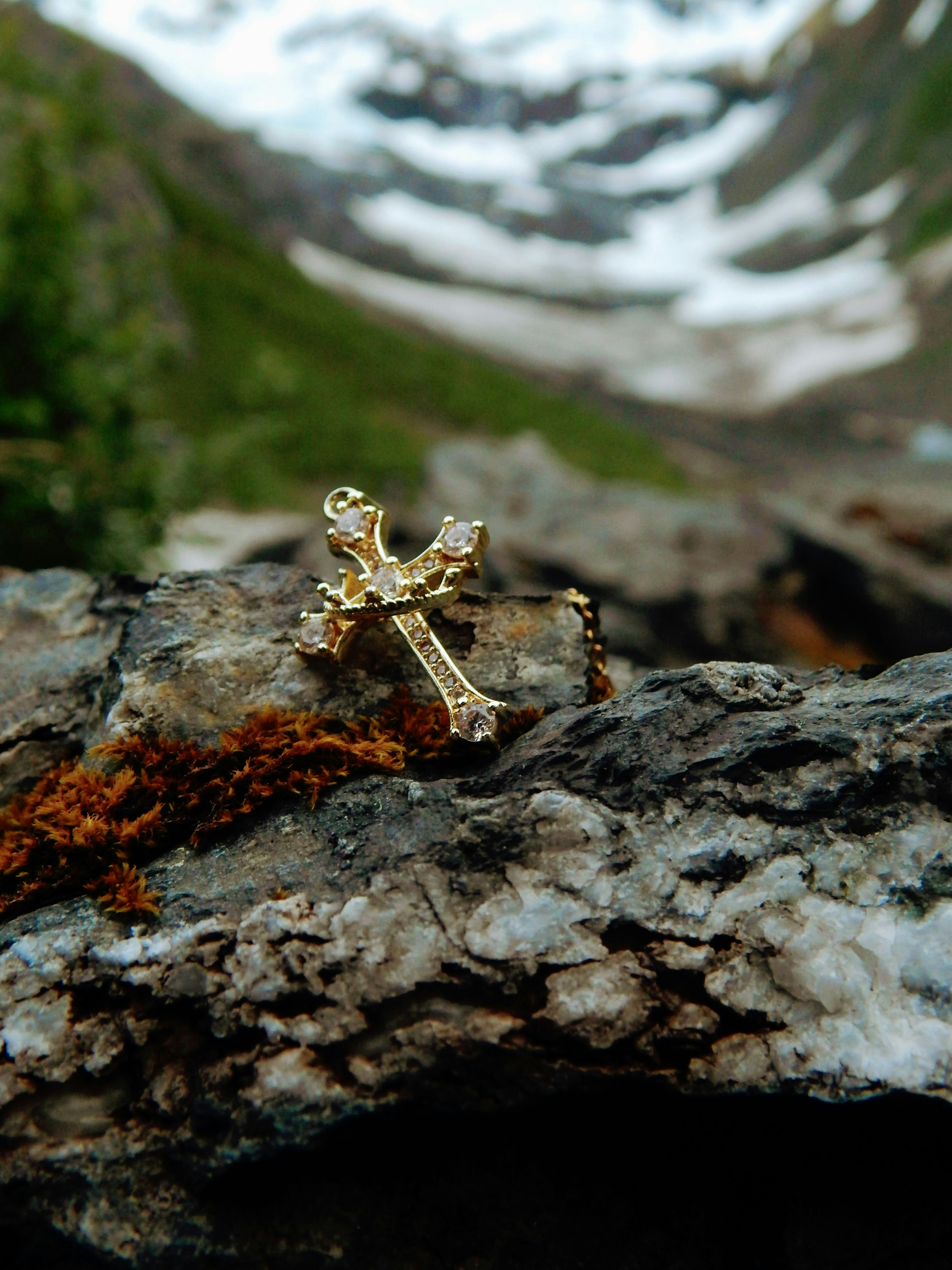 Golden jeweled cross on rock, snowy mountains background.