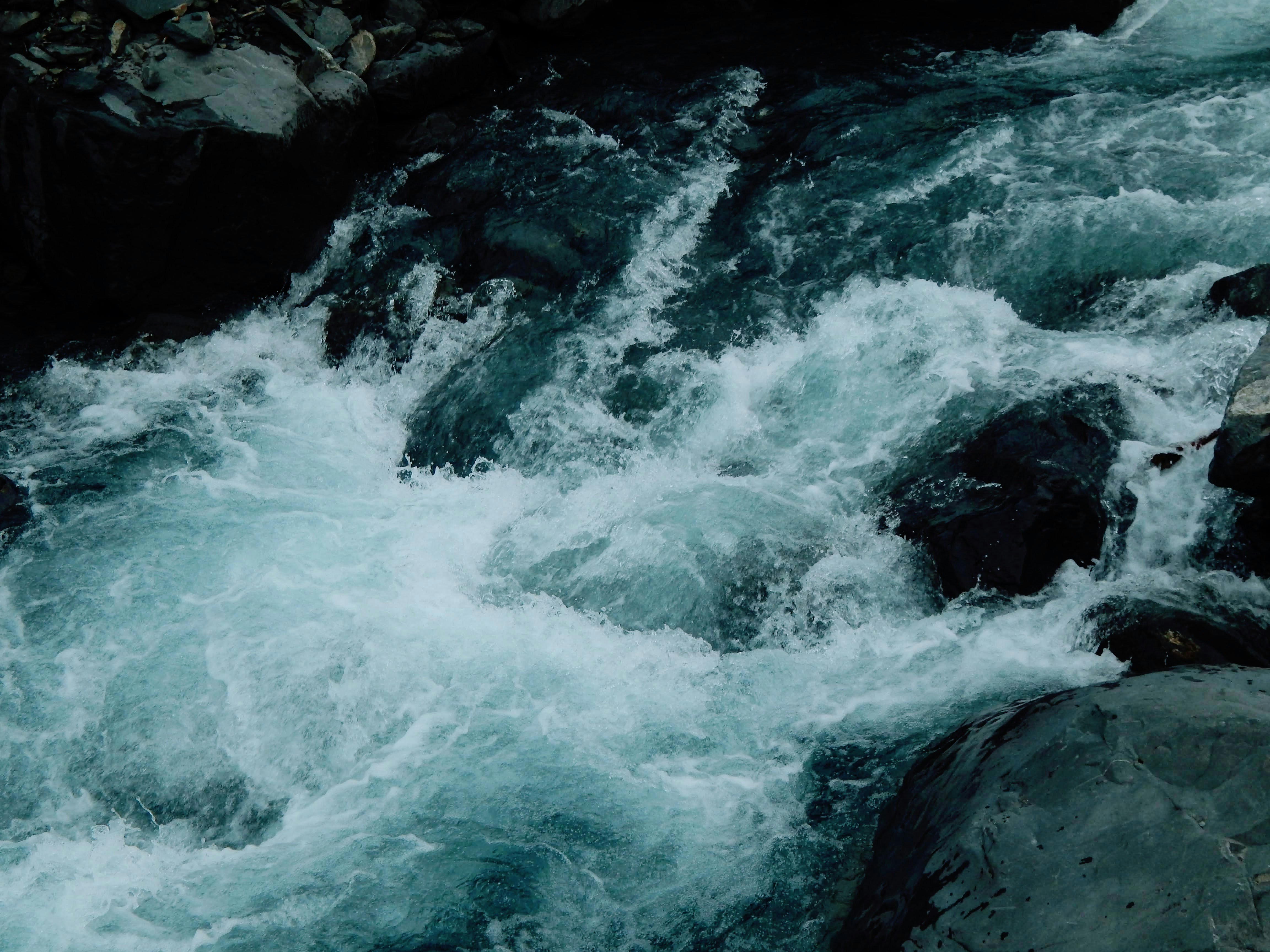 Turbulent blue water flowing over rocks in a river.