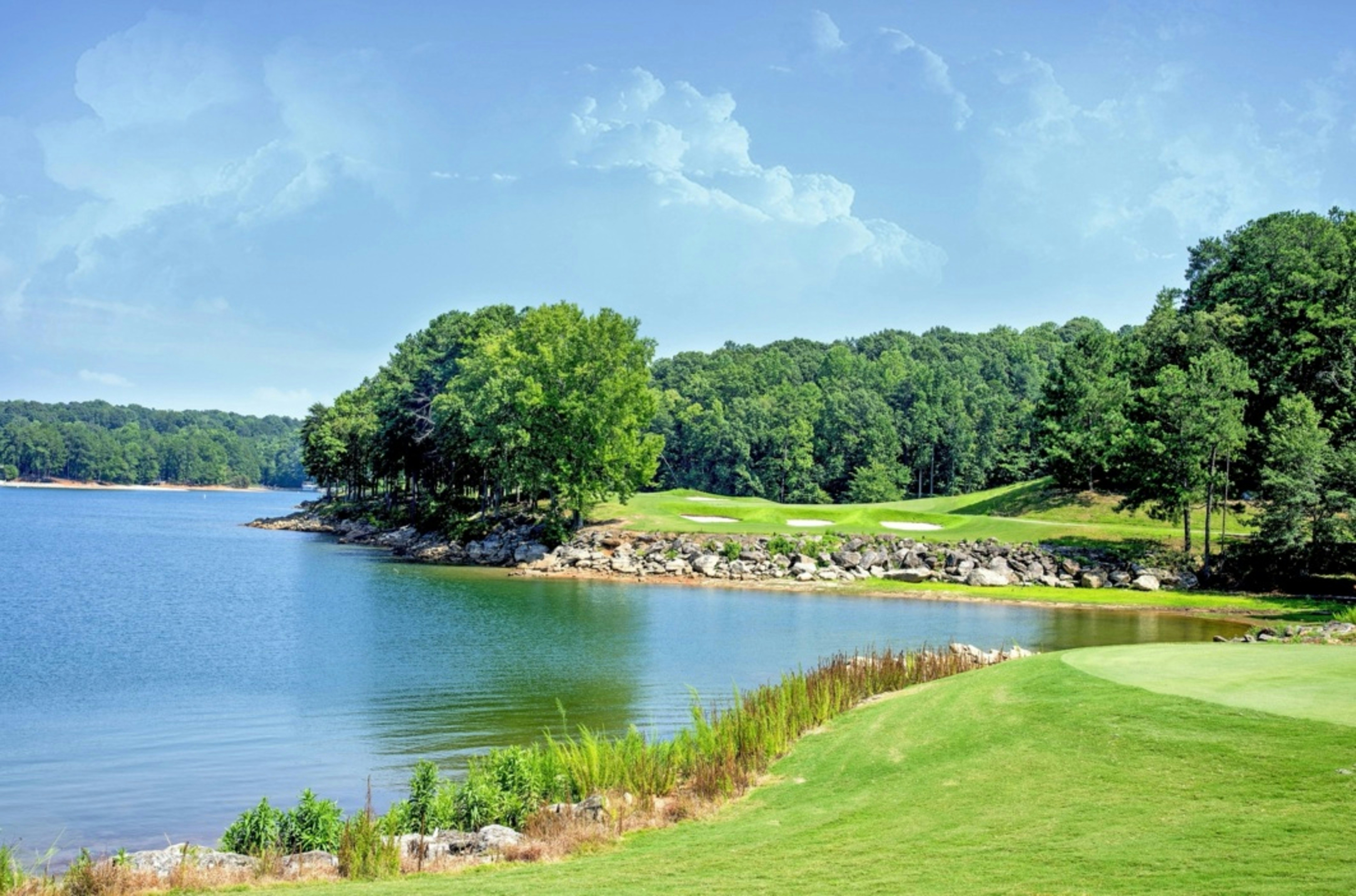 a lush lakeside golf course with greens and bunkers along a rocky shoreline