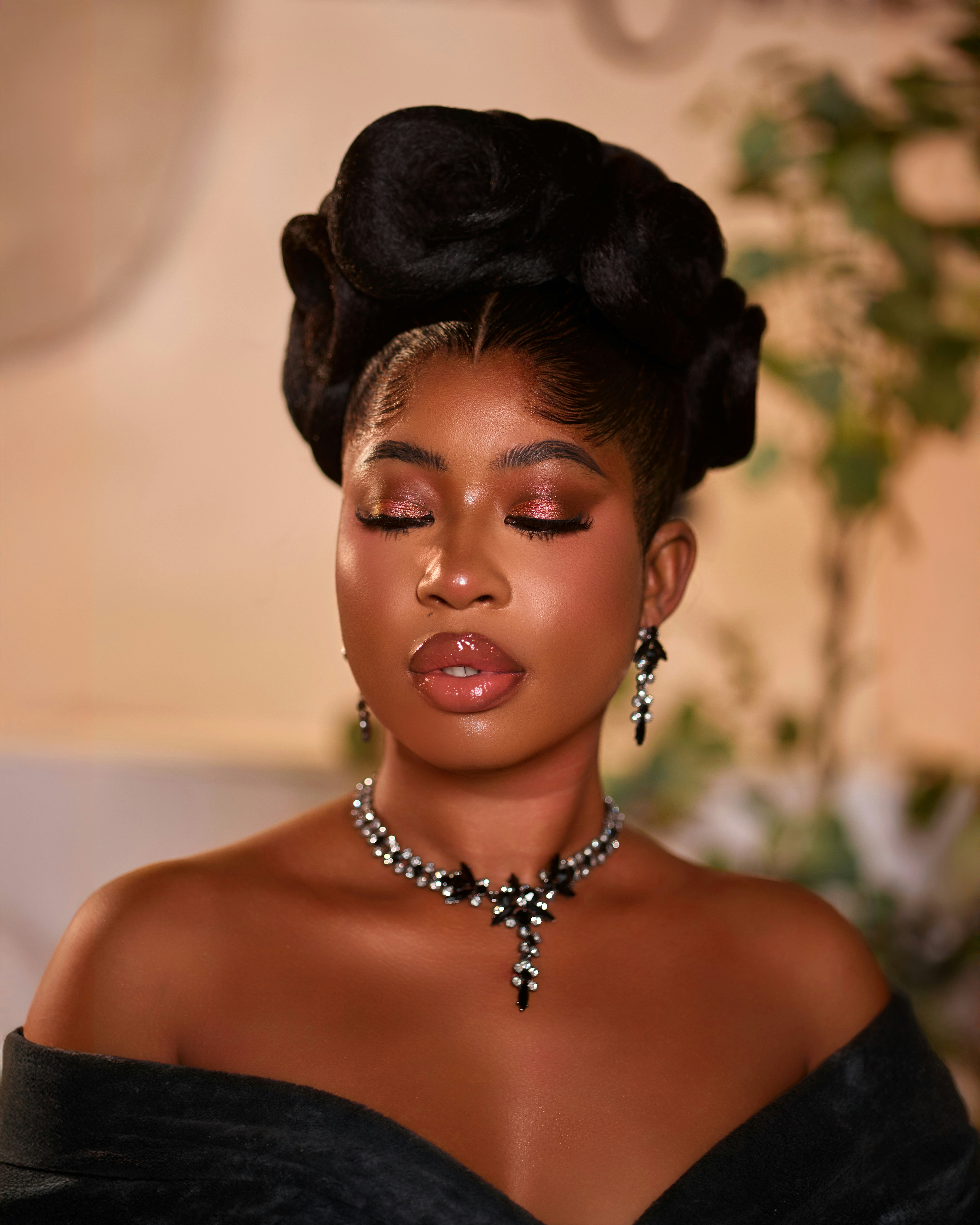 Belle femme avec un chignon élégant et un collier étincelant, les yeux fermés.
