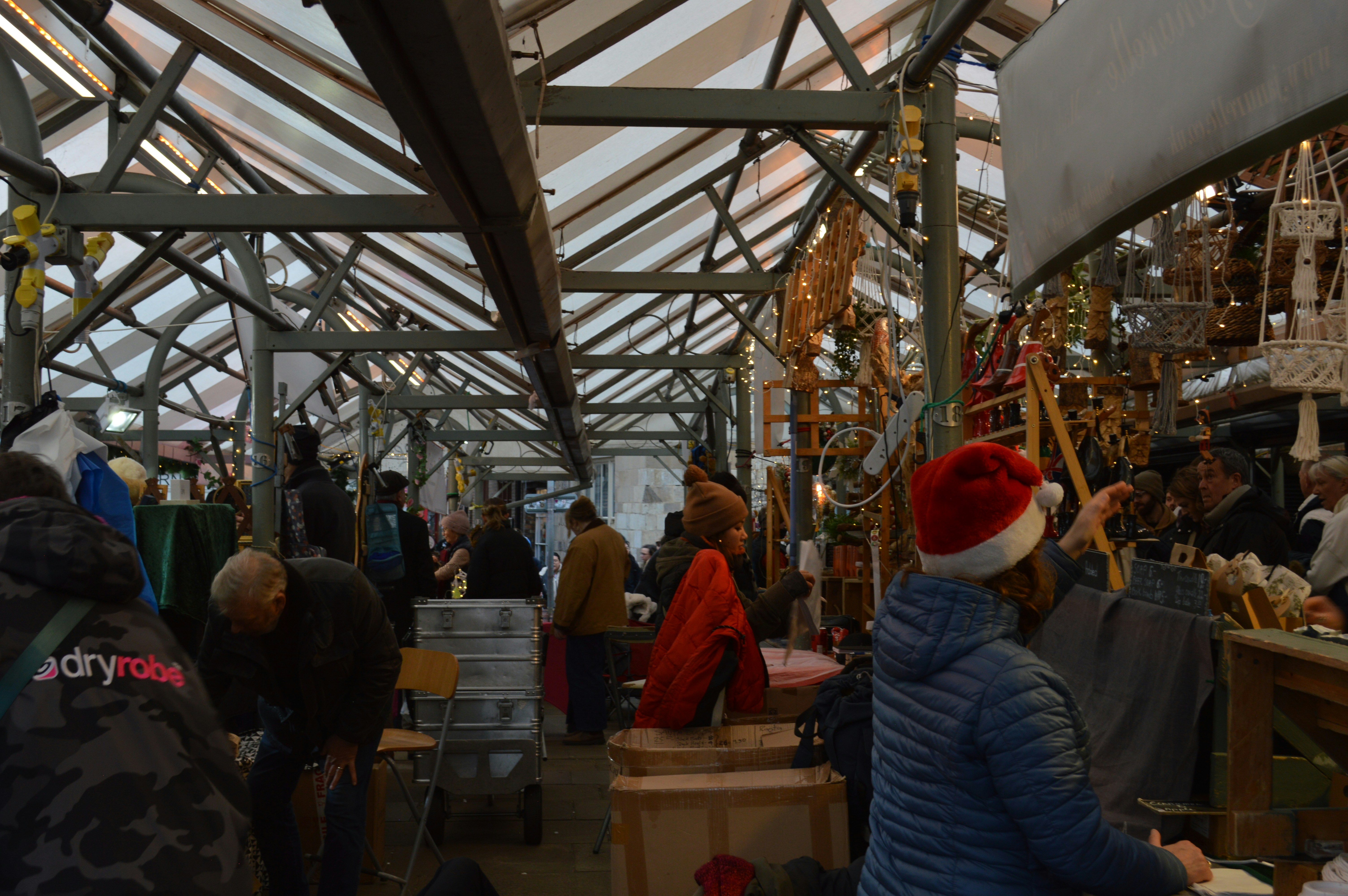 People browsing stalls at a bustling indoor holiday market.