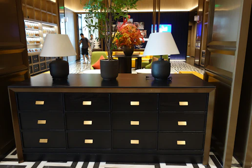 Elegant black dresser with two lamps and a floral arrangement
