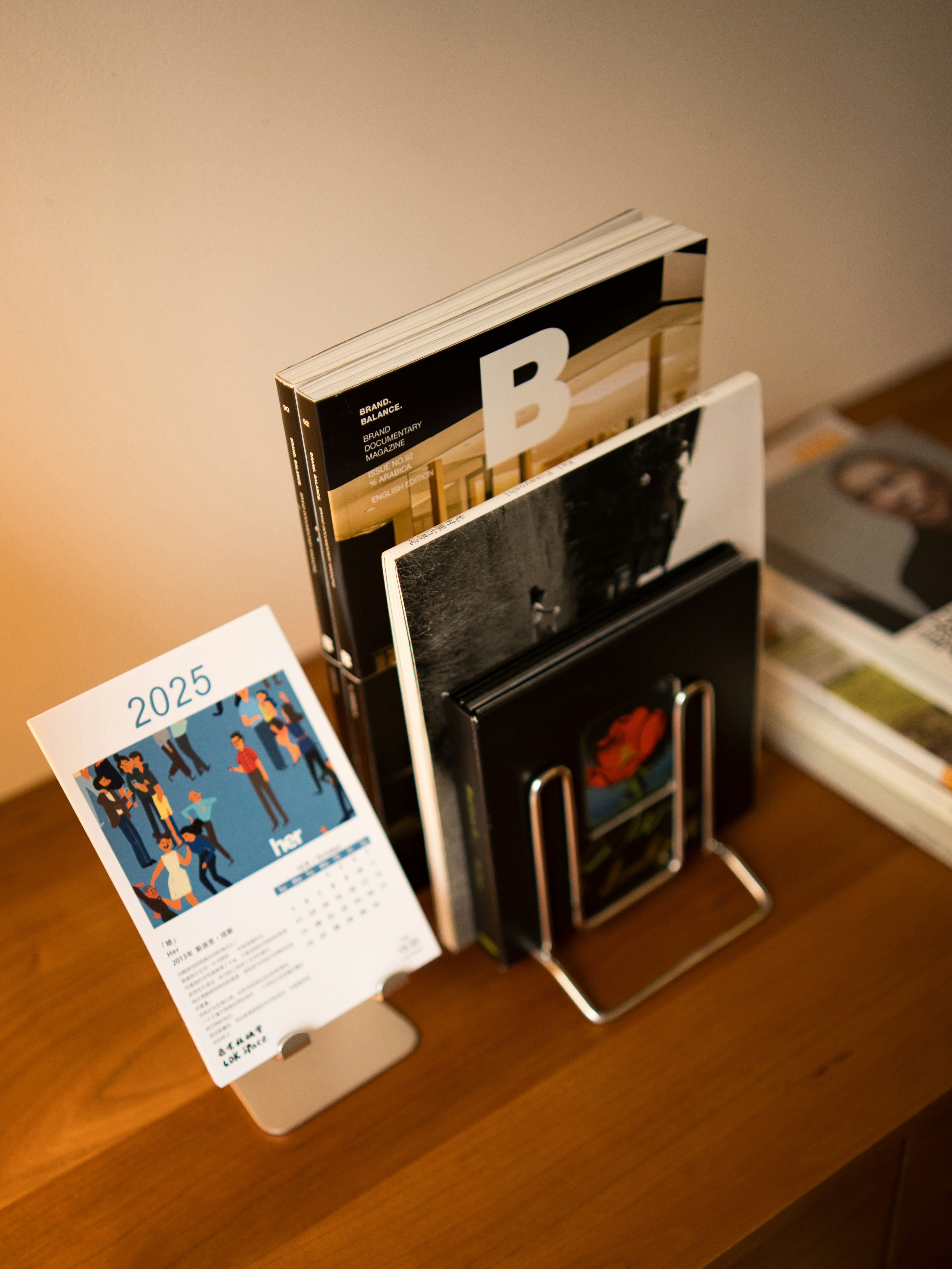 A 2025 calendar and magazines on a wooden table.