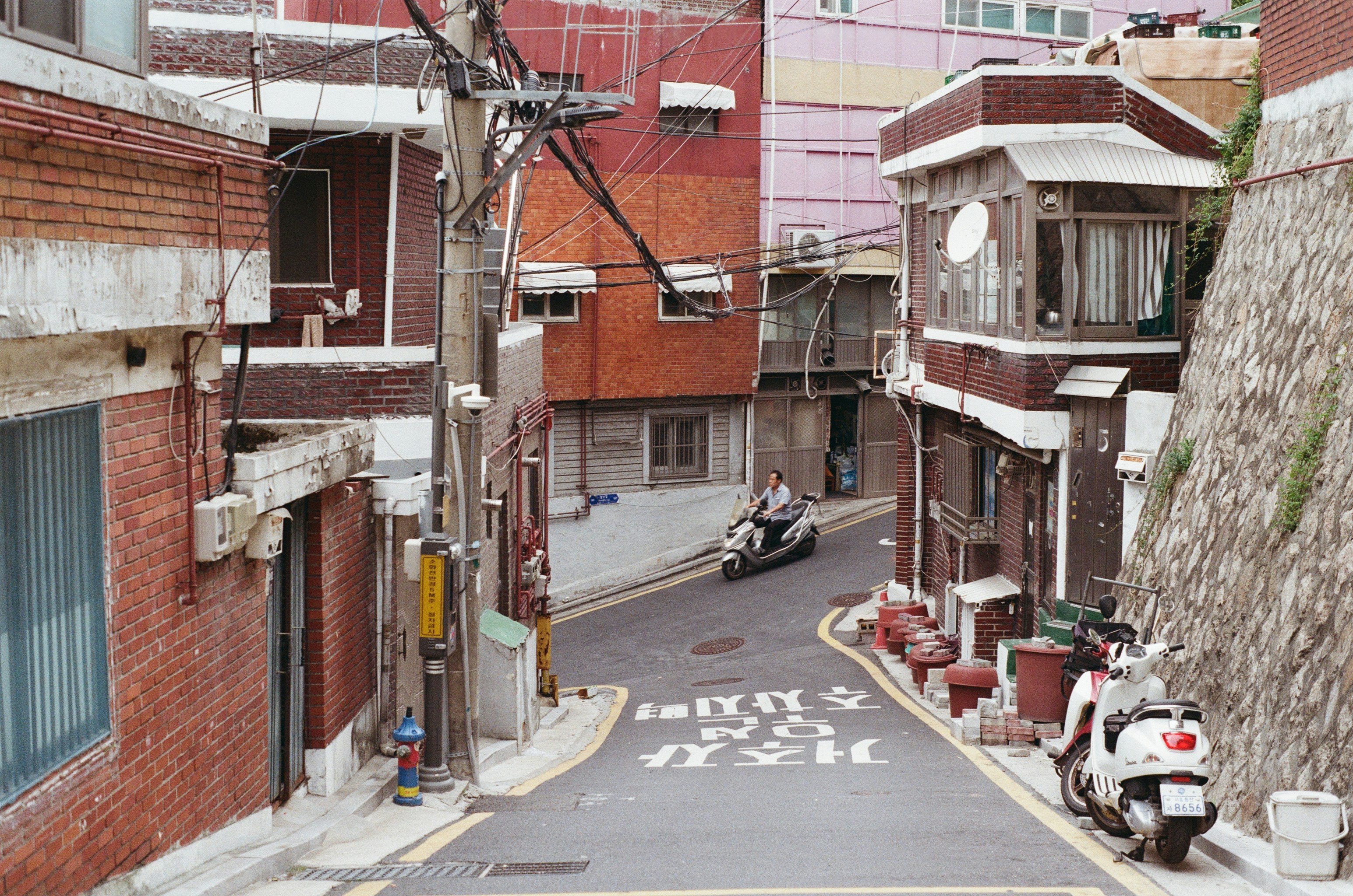 Scooter on a winding urban street lined with buildings