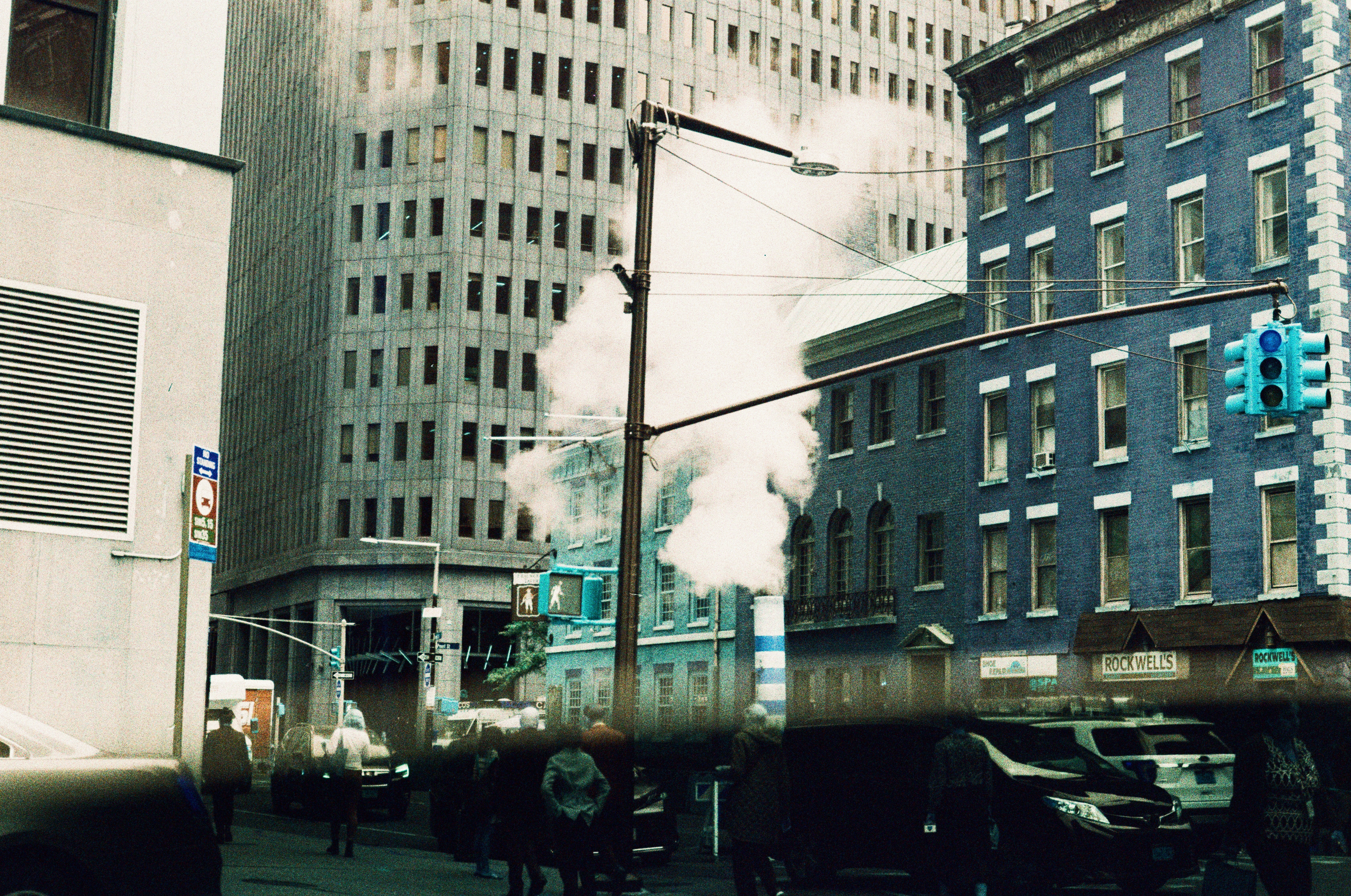 Steam billows from a city street with tall buildings