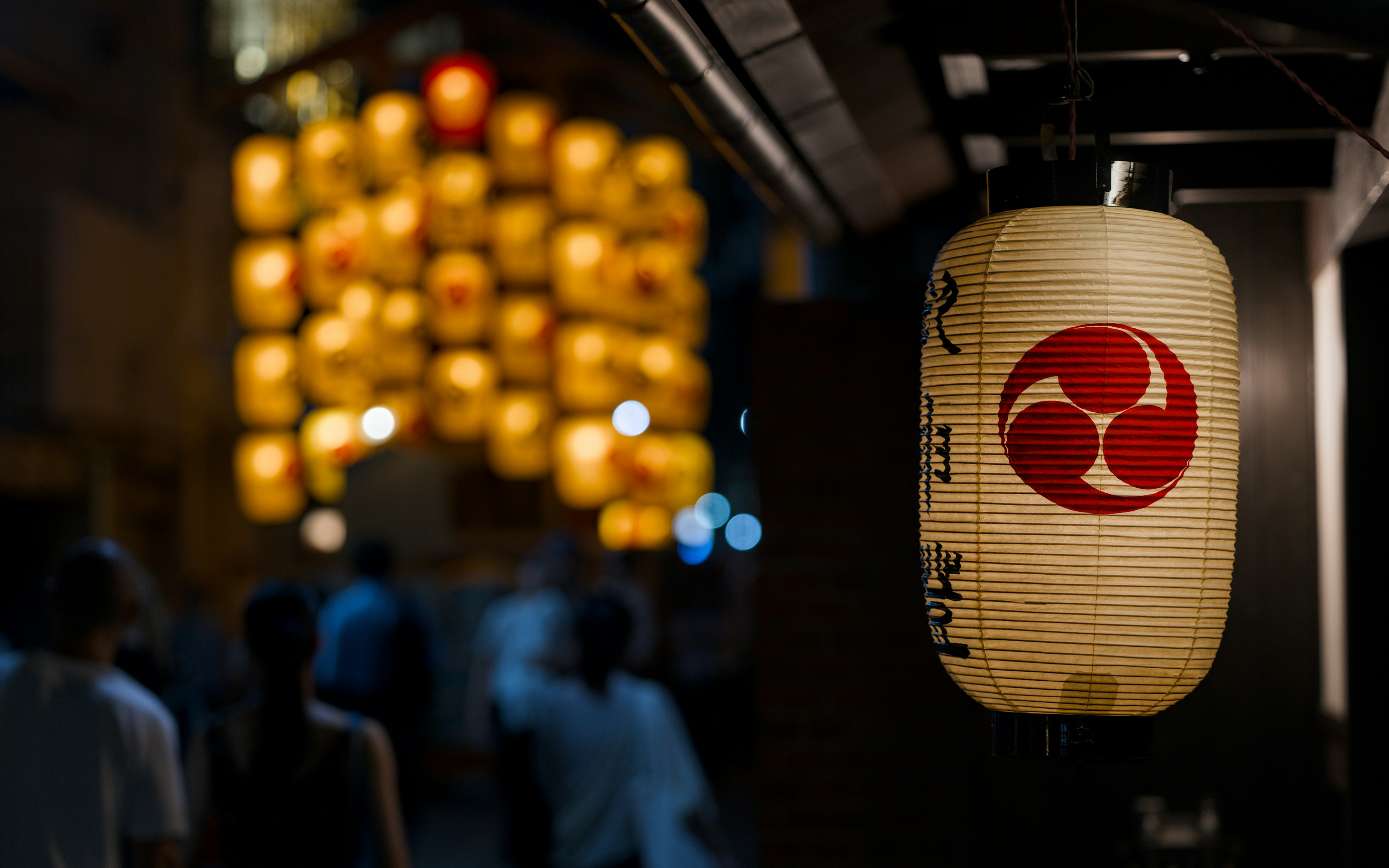 Lanterne japonaise blanche avec un symbole rouge et des lanternes jaunes floues.