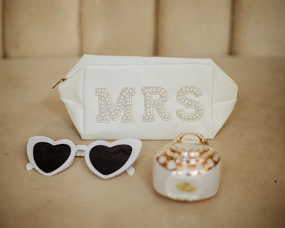 White makeup bag, heart sunglasses, and perfume bottle