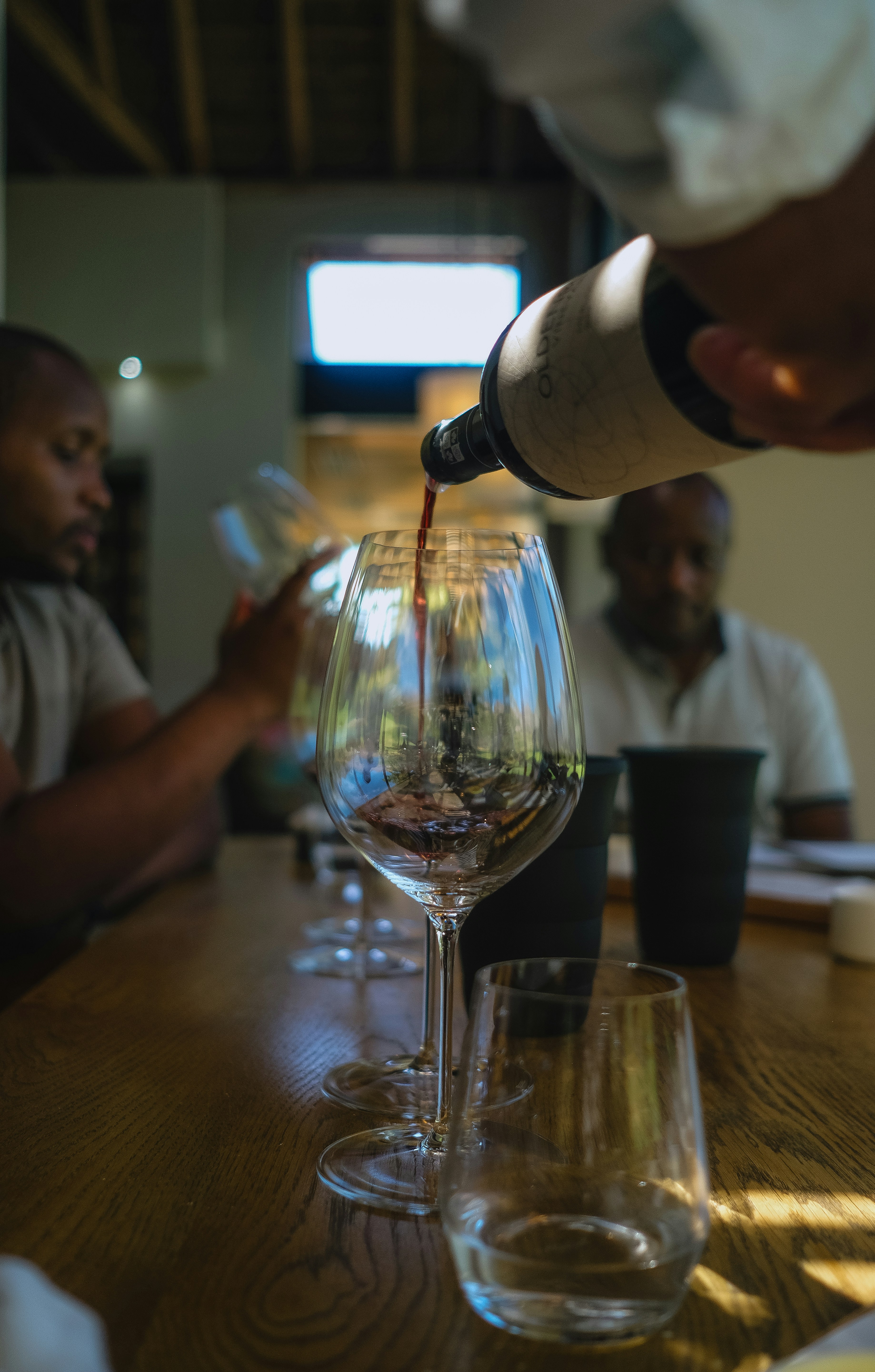 Dark red wine poured into a glass at a tasting table
