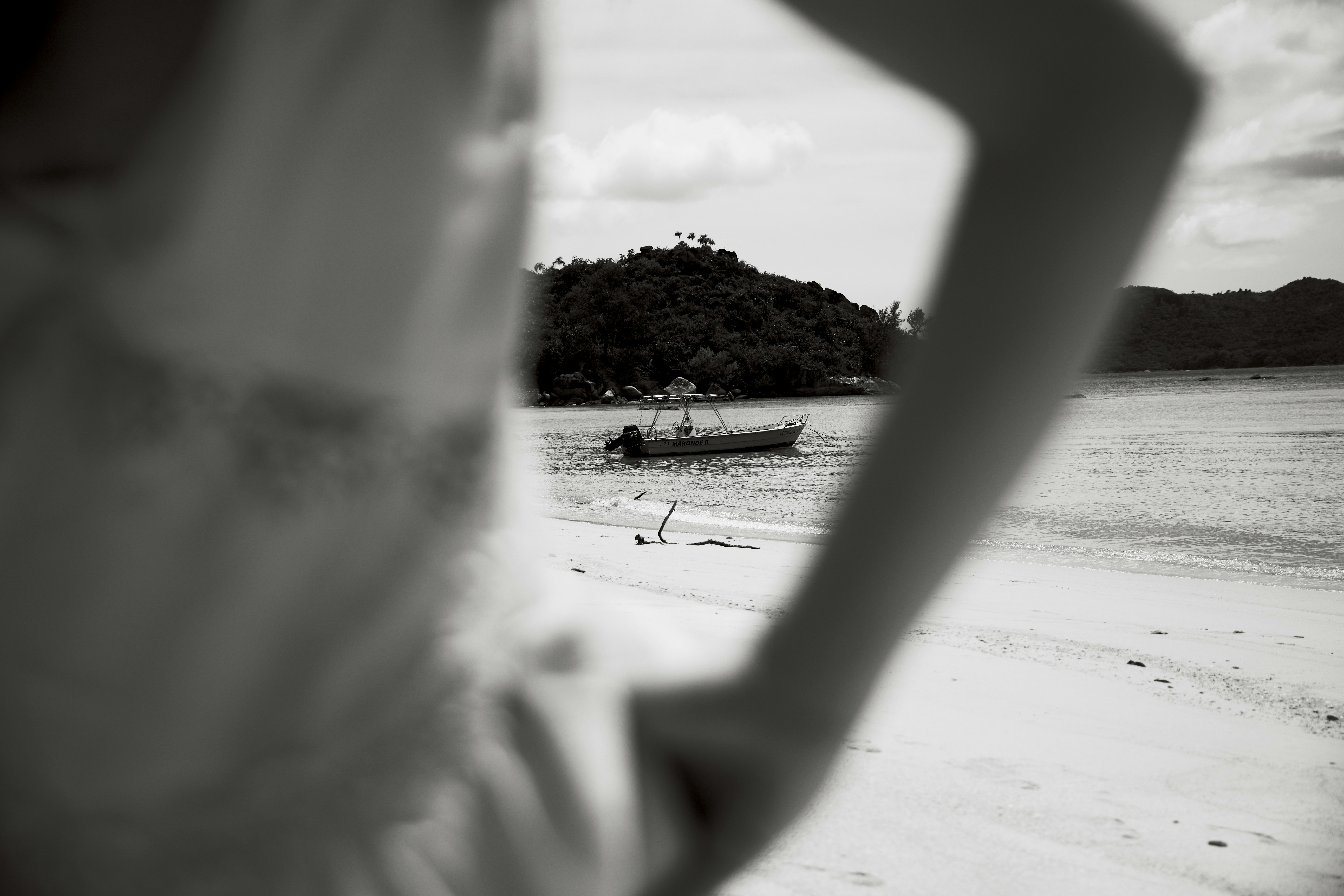 Person on sandy beach with boat and hill