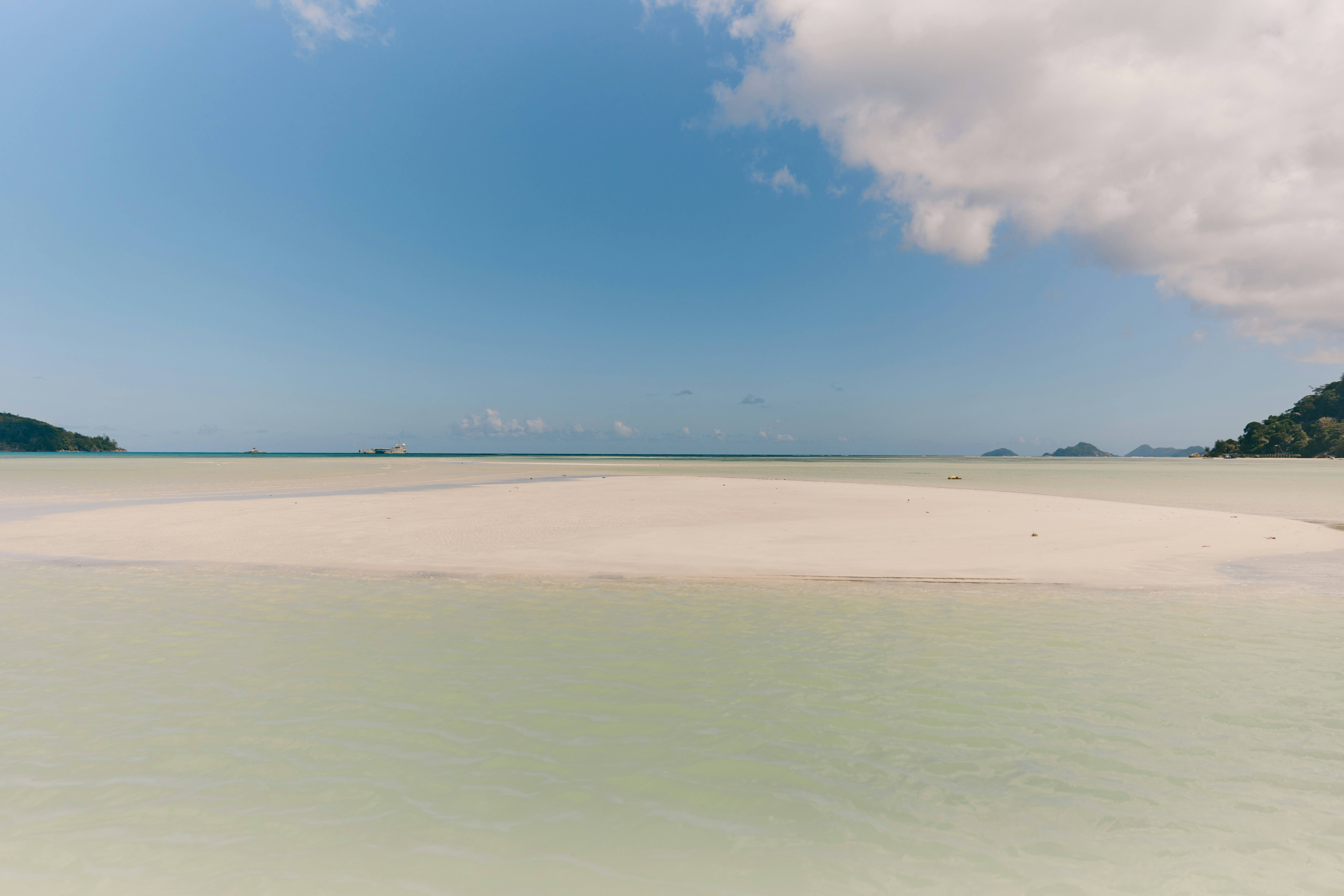 White sandbar in shallow water, blue sky