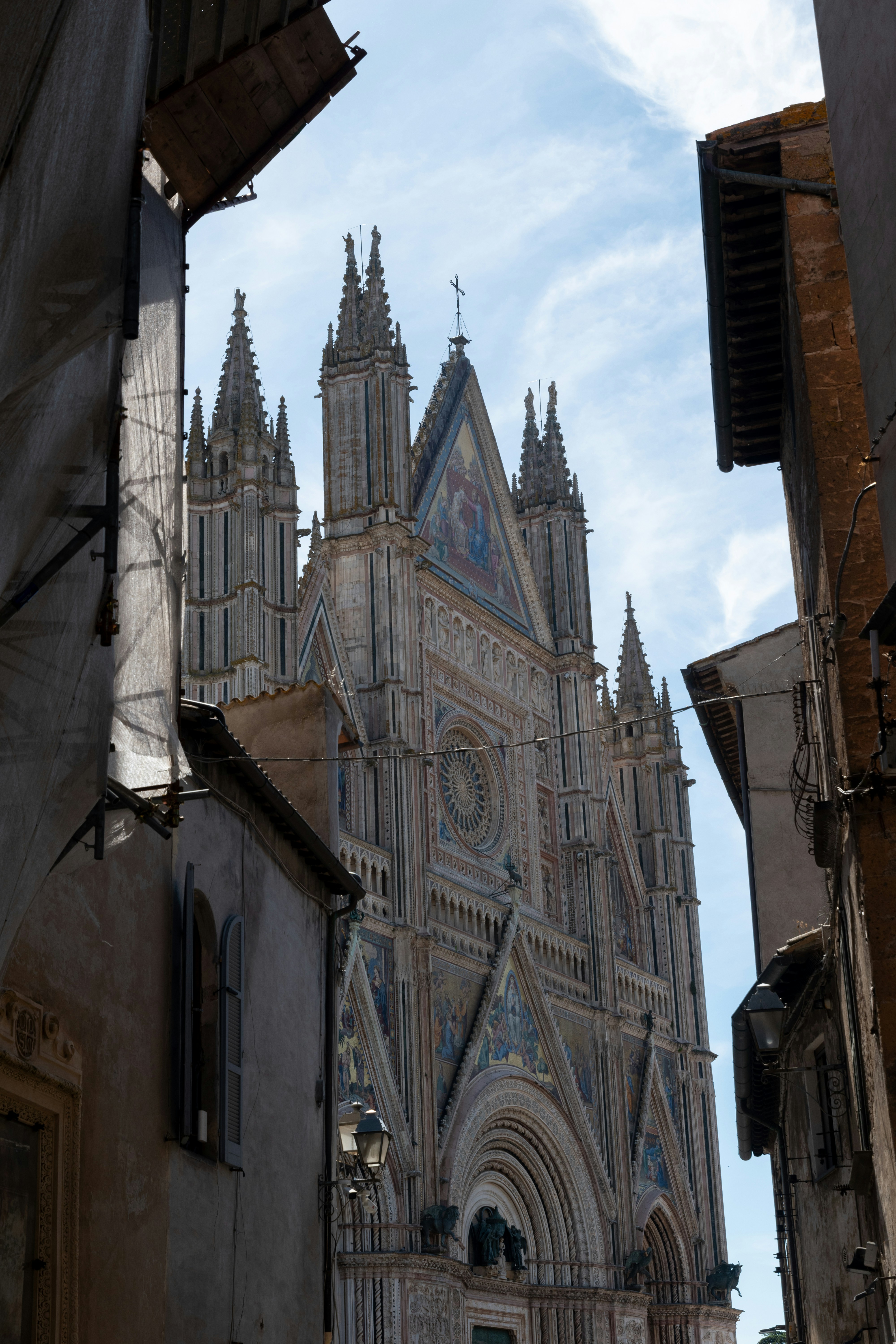 Katedral Orvieto dibingkai oleh bangunan jalan sempit di bawah langit biru