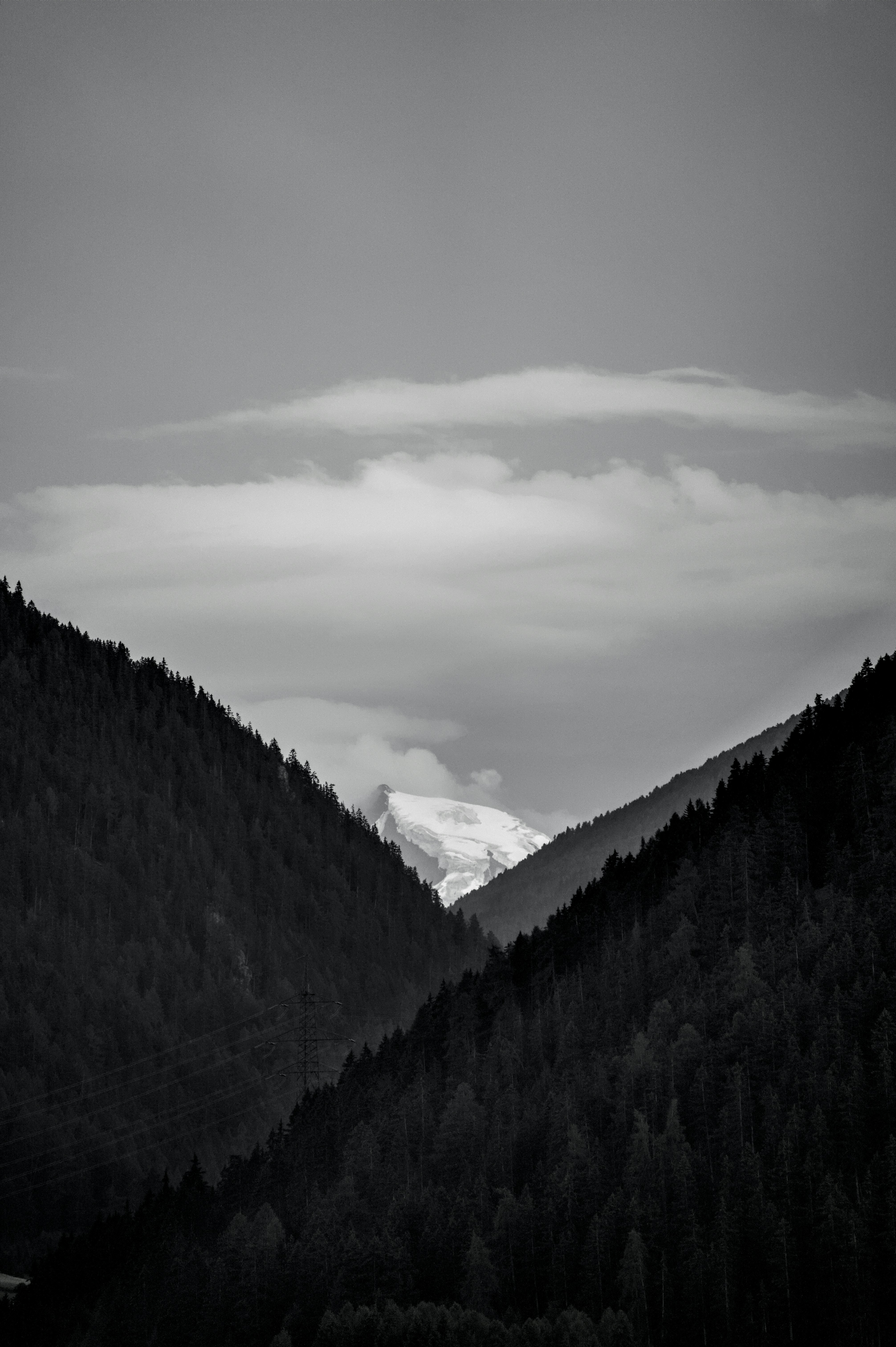 Distant snow peak visible between dark forested mountain slopes.