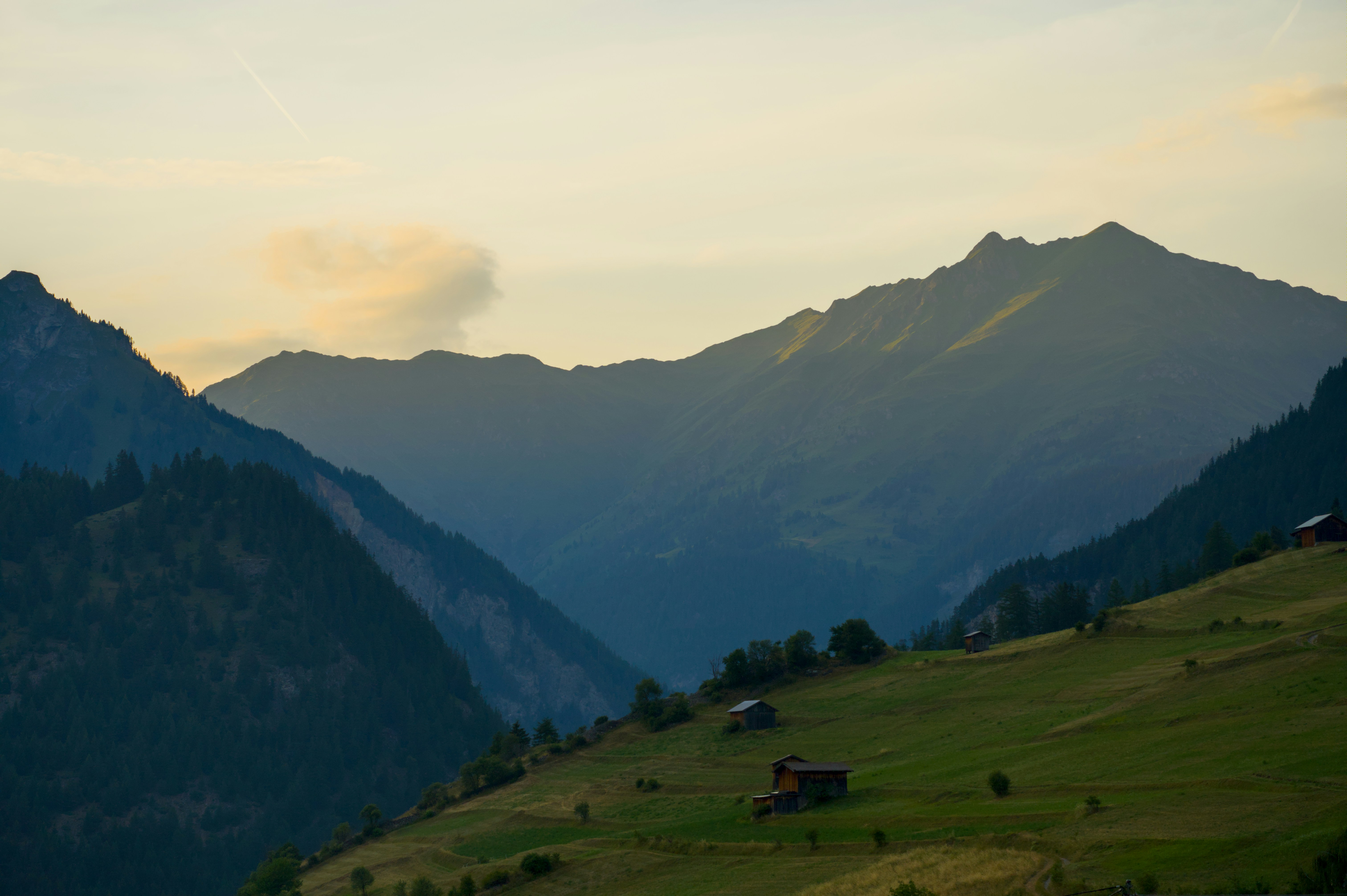 Silhouetted mountains and green hillsides at sunrise or sunset.
