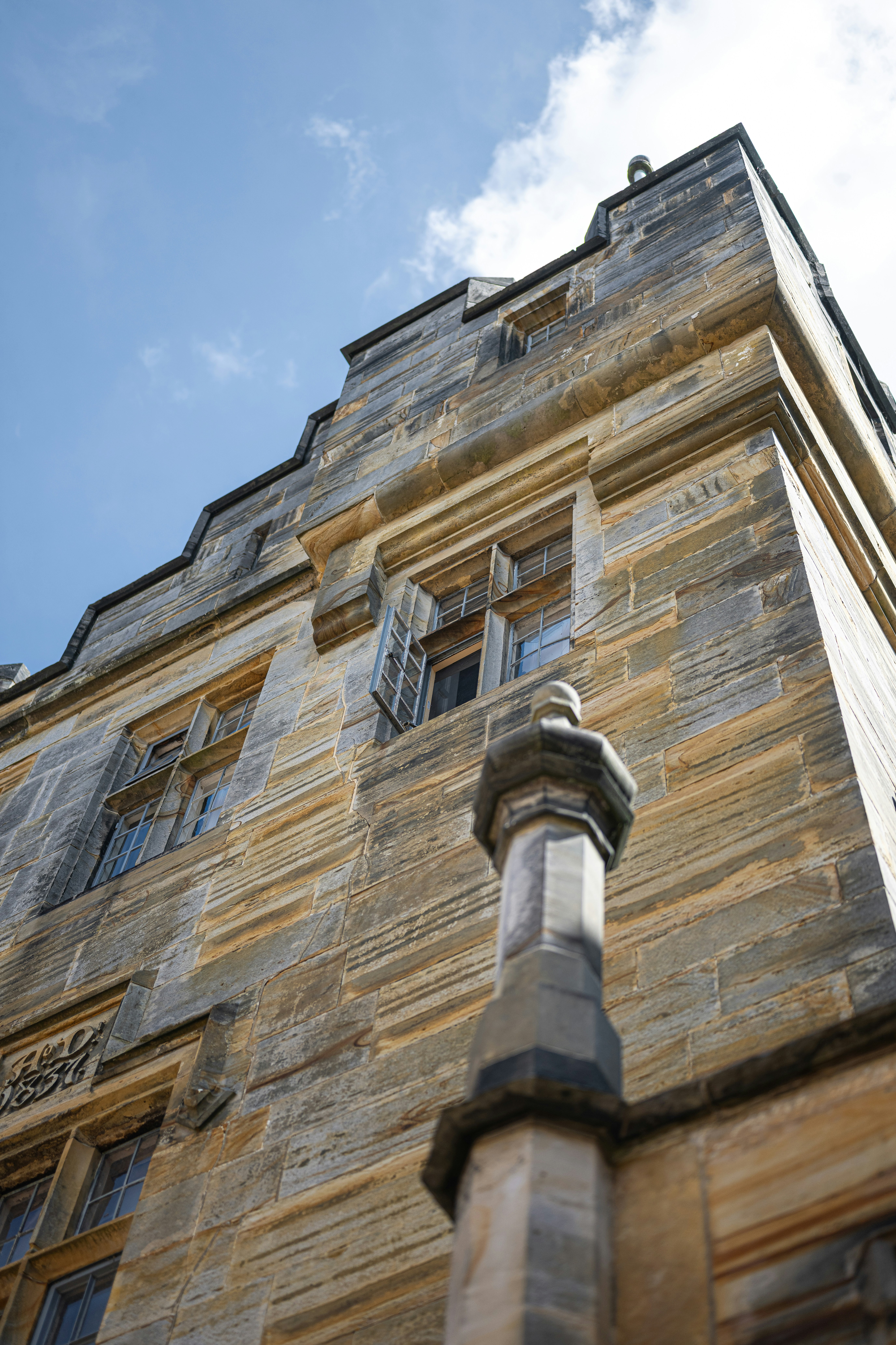 Edificio histórico de piedra con ventanas abiertas contra un cielo azul.