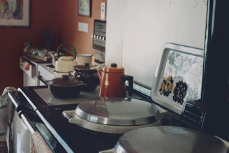 Cooking pots, kettles, and a tray on a kitchen stove