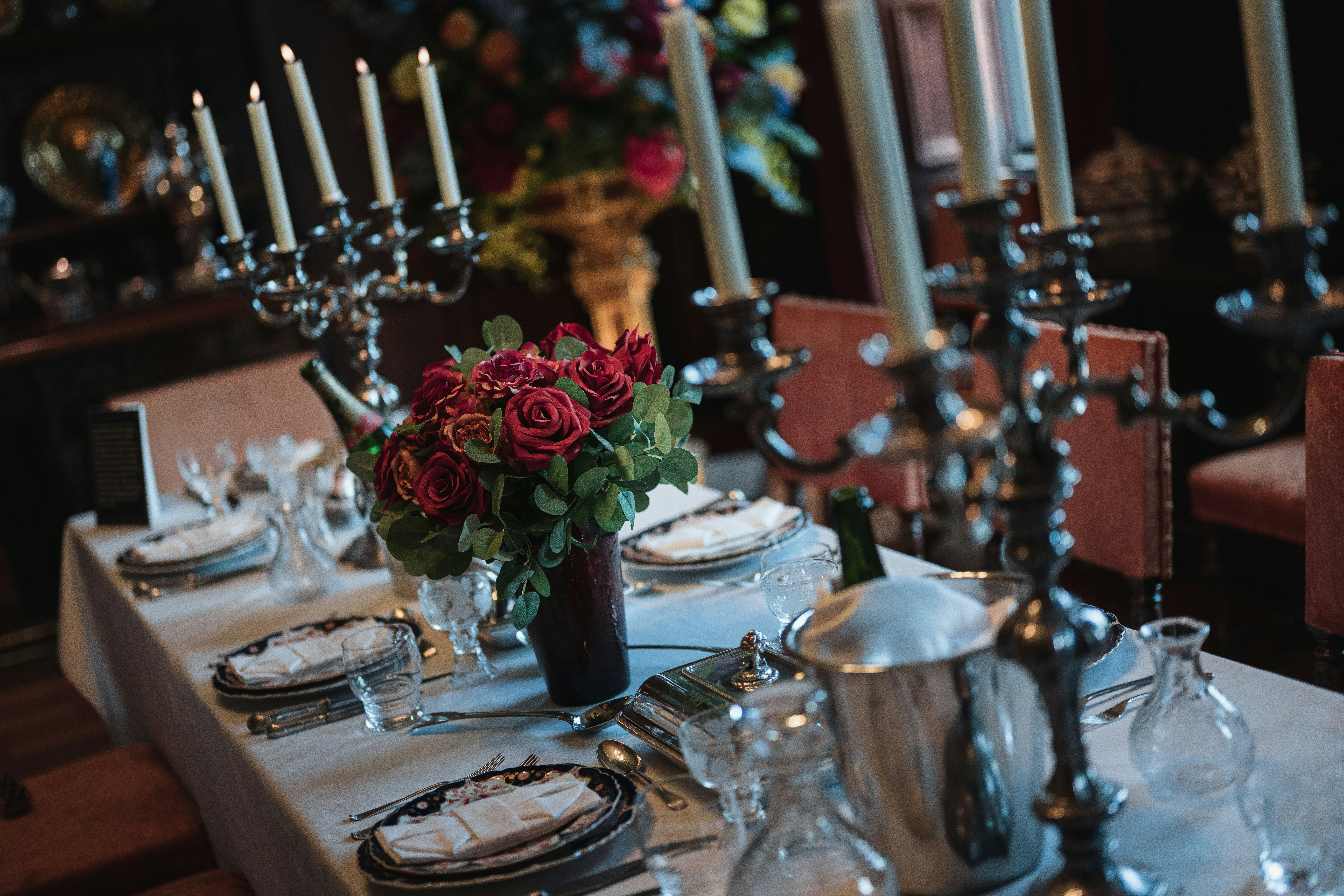 Una mesa formal de comedor con candelabros y rosas rojas.