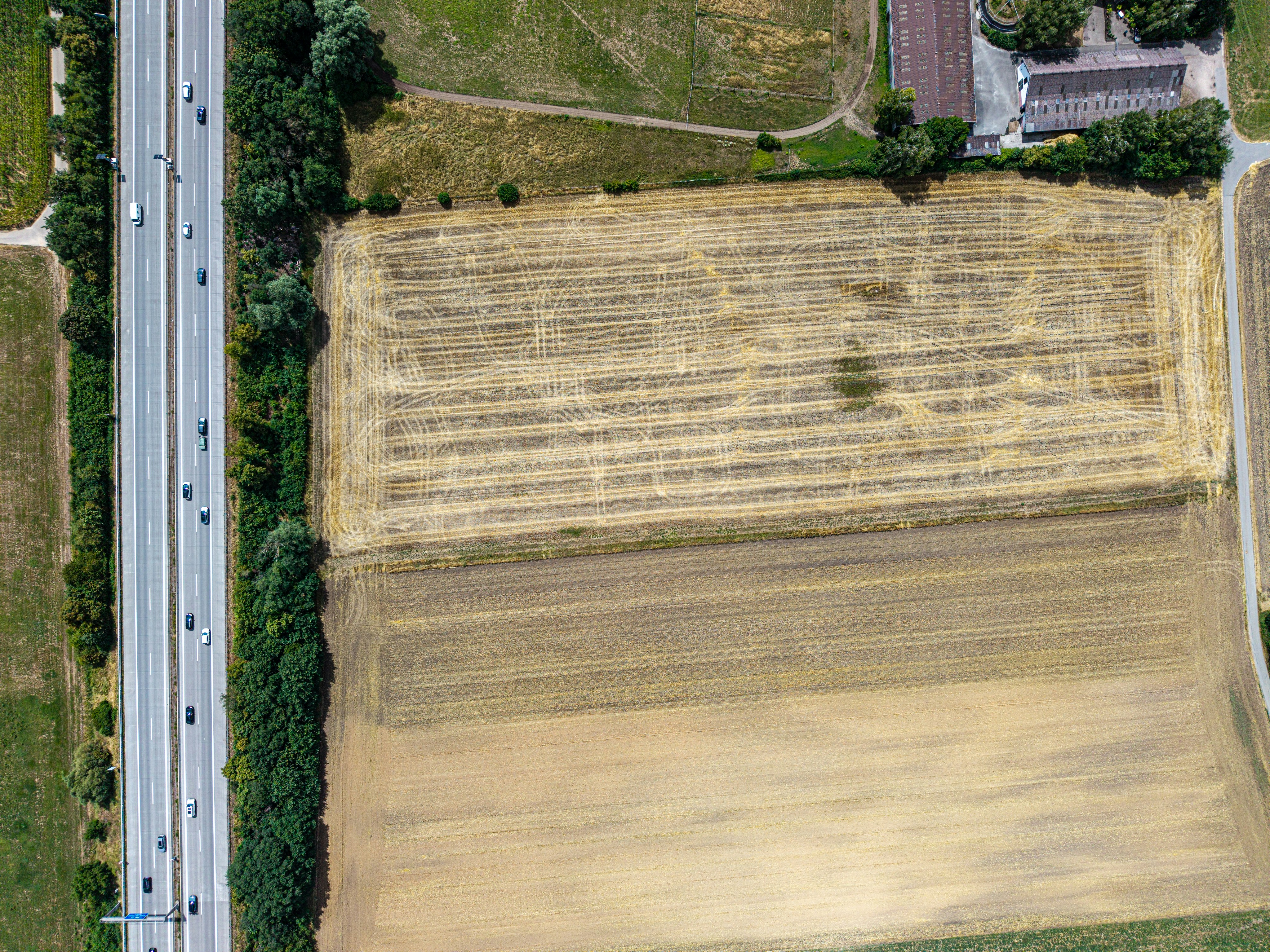 Aerial view of a highway next to harvested agricultural fields.