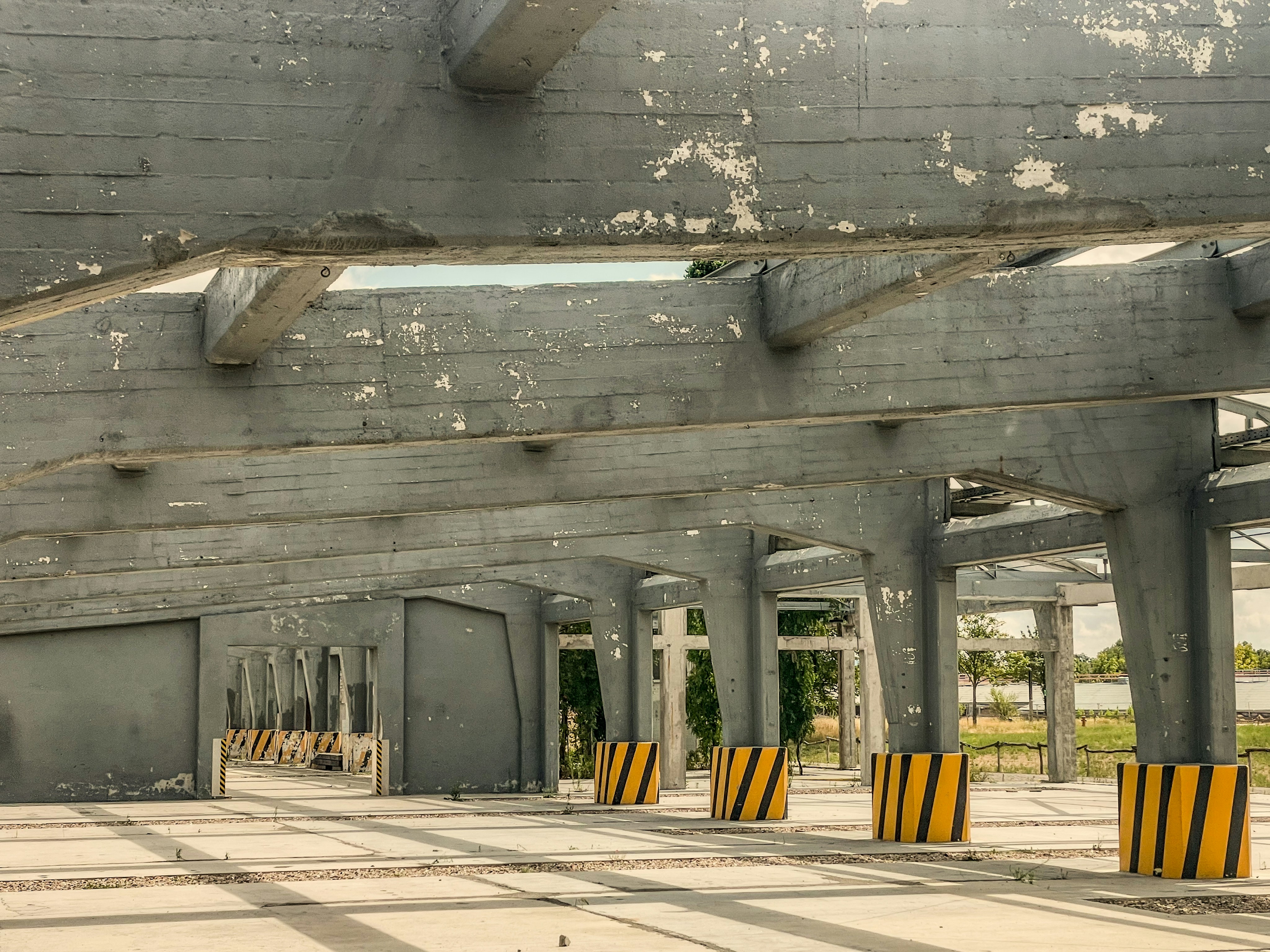 Weathered concrete structure with peeling paint and striped barriers.