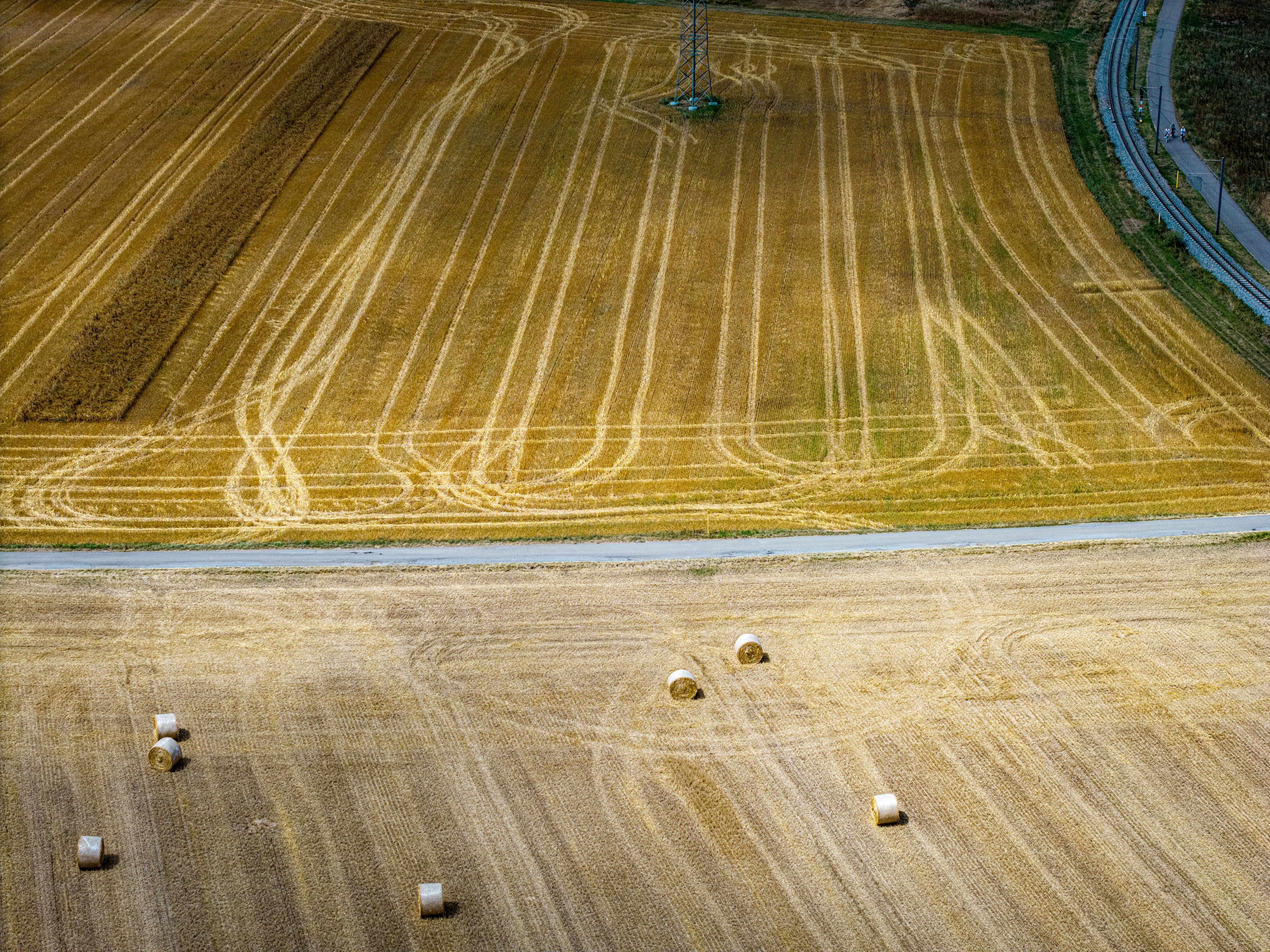 Golden field with hay bales and a winding road.