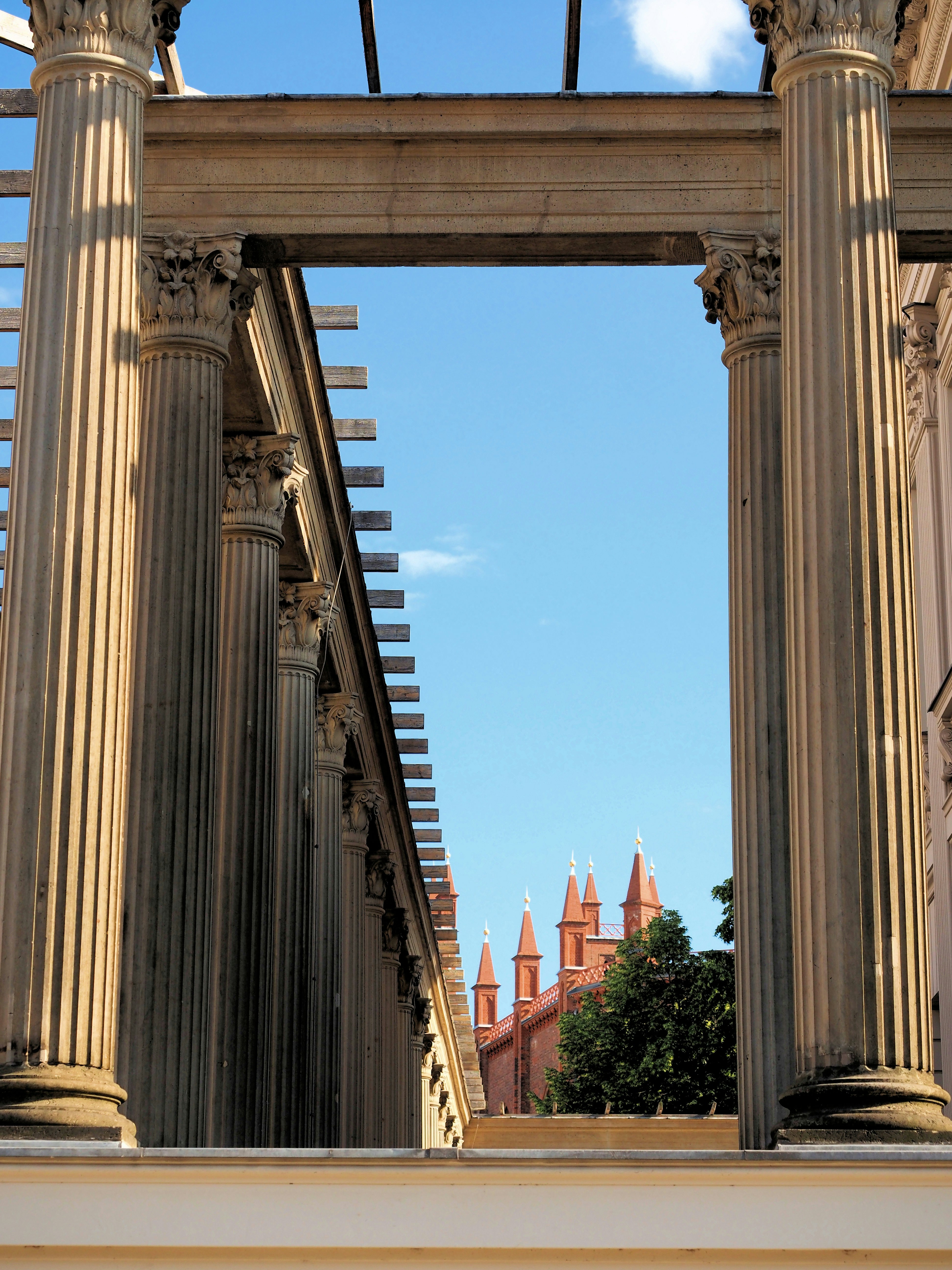 Stone columns frame red spires against a clear blue sky