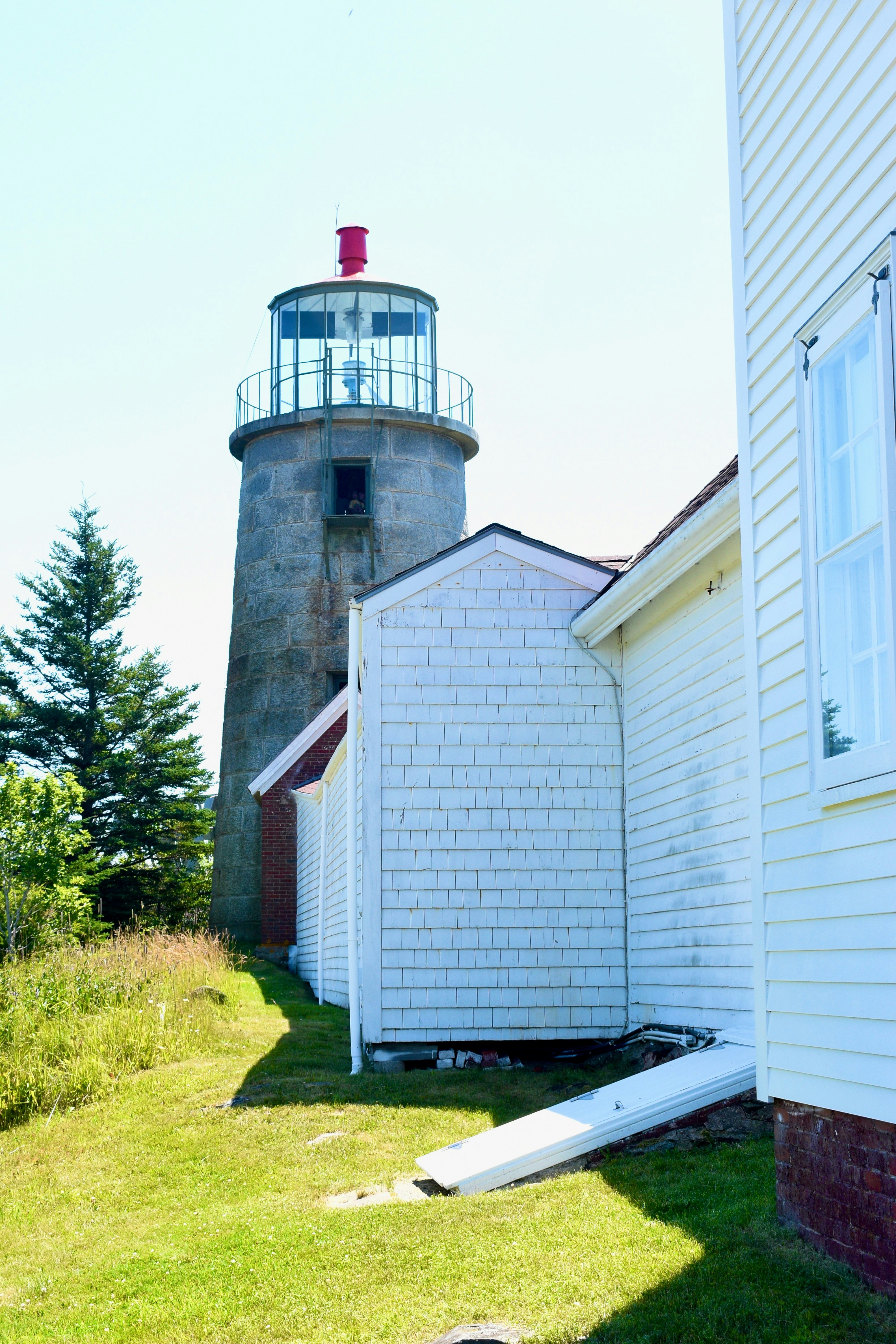 Historic stone lighthouse beside a white building