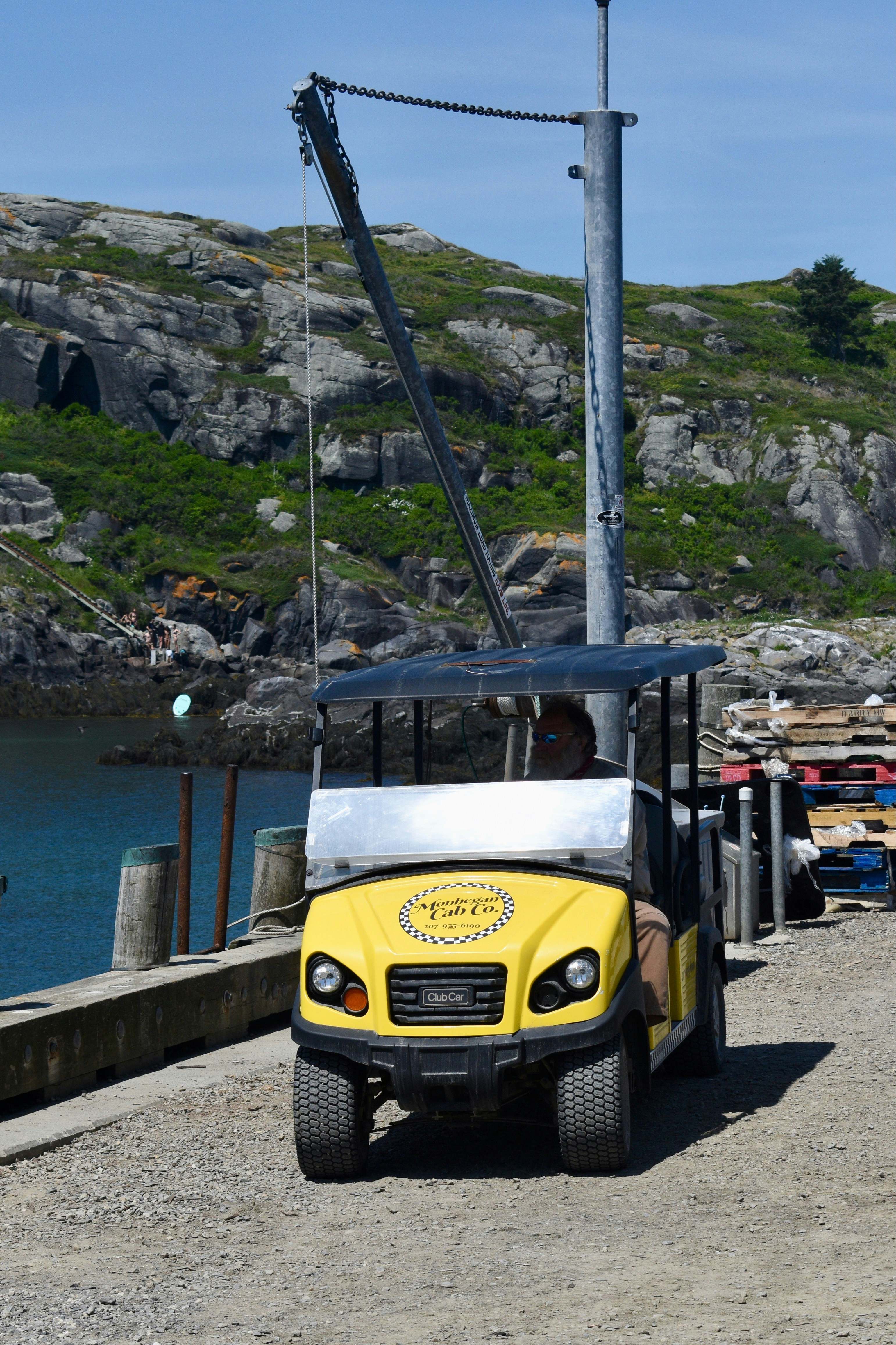 Yellow golf cart on a dock with rocky hills